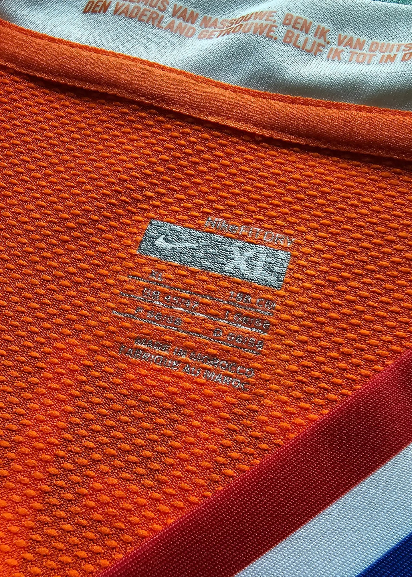 Detail view showing size label and Nike branding on an orange football shirt.