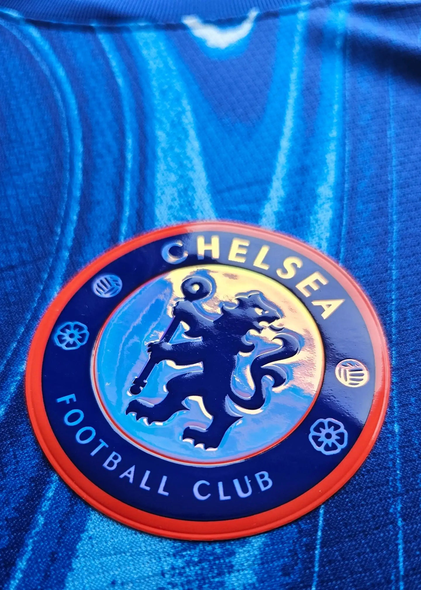 Detail view of Chelsea Football Club crest with lion holding a staff, surrounded by blue background.