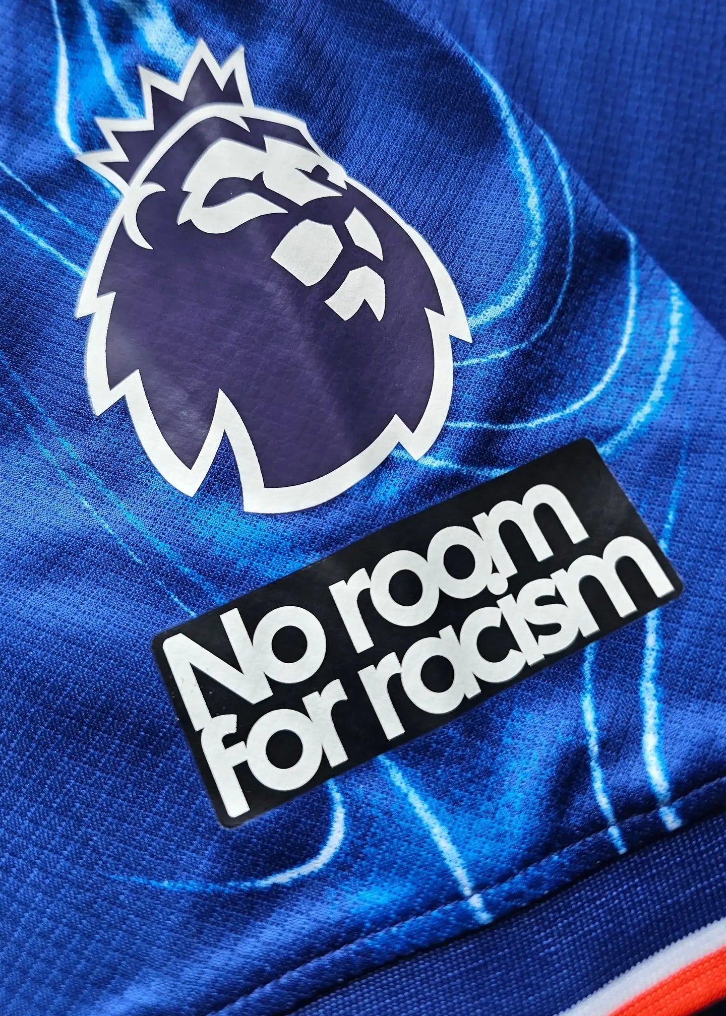 Detail showing the Premier League crest and 'No room for racism' message on shirt.