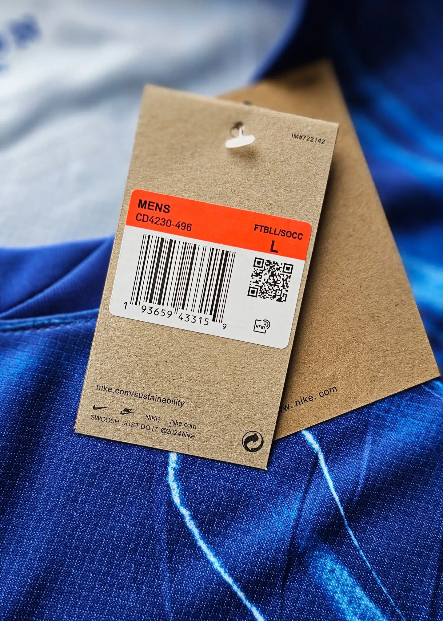 Size L tag showing Nike branding and QR code details on a blue football shirt.