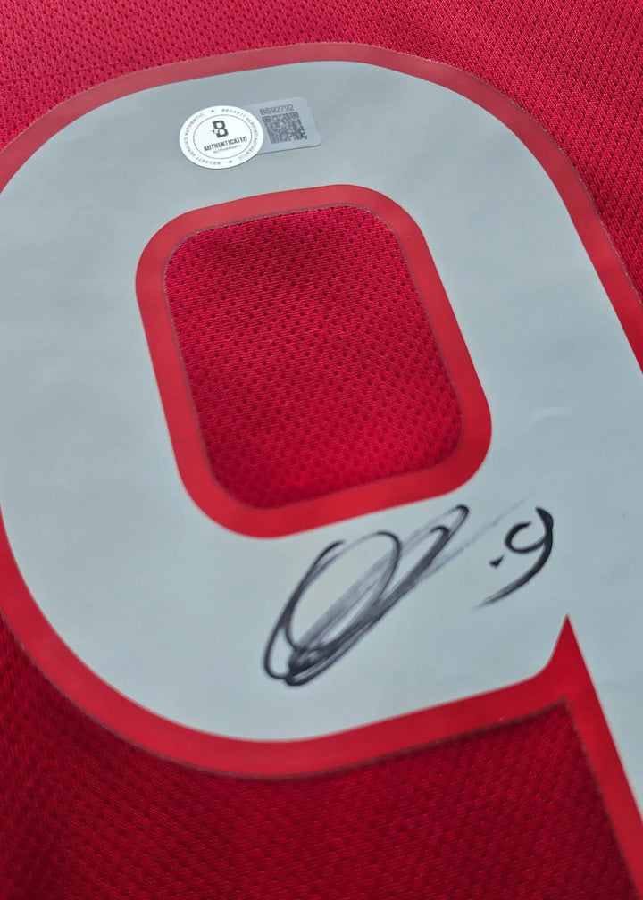 Detail featuring No. 9 and signature on a red football shirt.