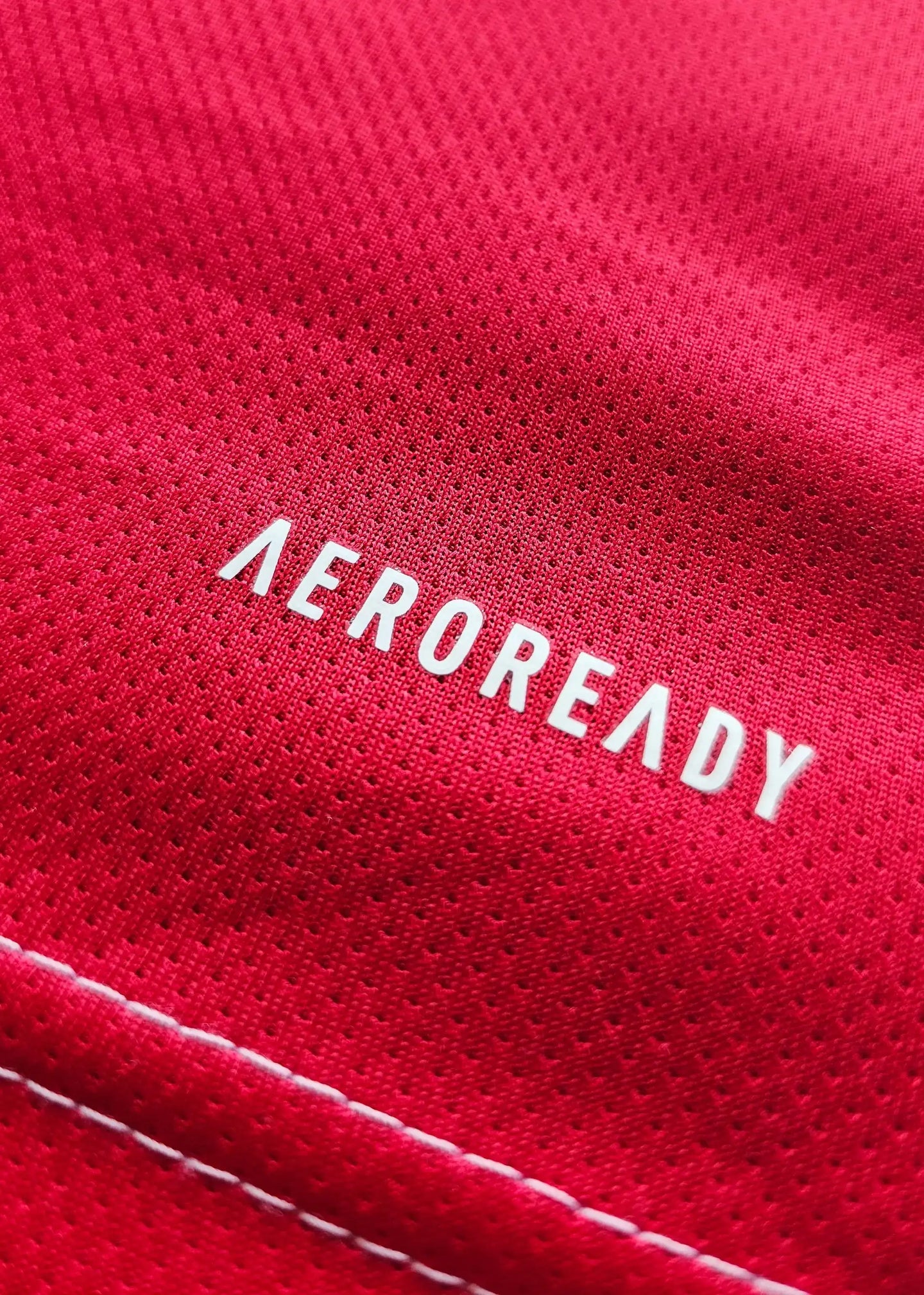Close-up showing the word 'AEROREADY' on the red fabric of the football shirt.