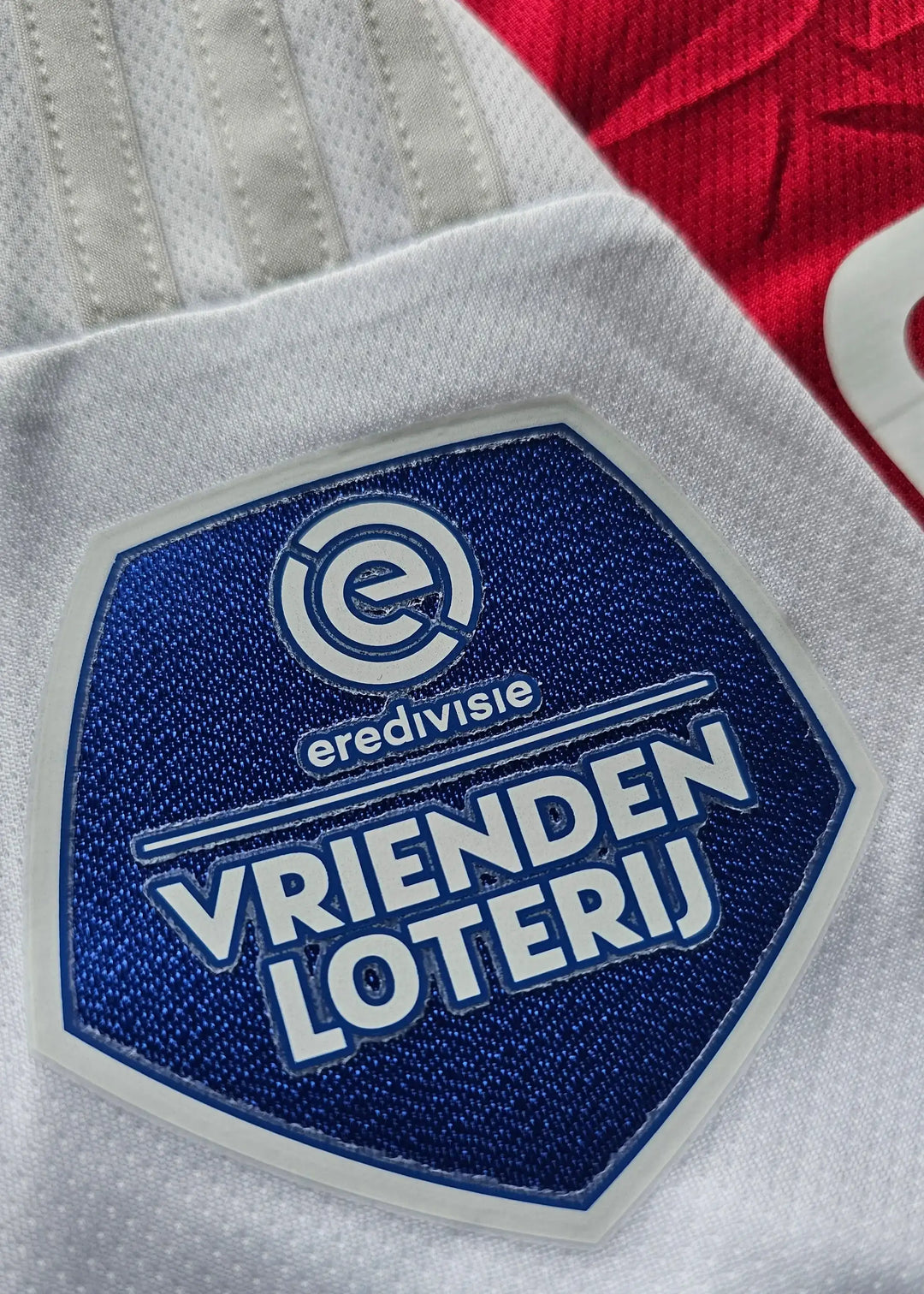Detail view of Vrienden Loterij badge and Eredivisie text on the signed Ajax football shirt.