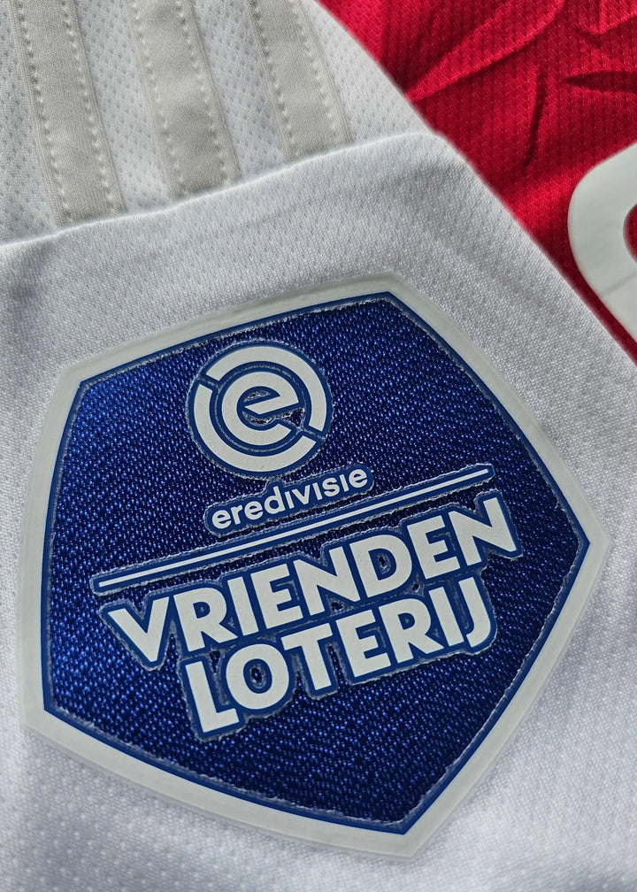 Detail view of Vrienden Loterij badge and Eredivisie text on the signed Ajax football shirt.