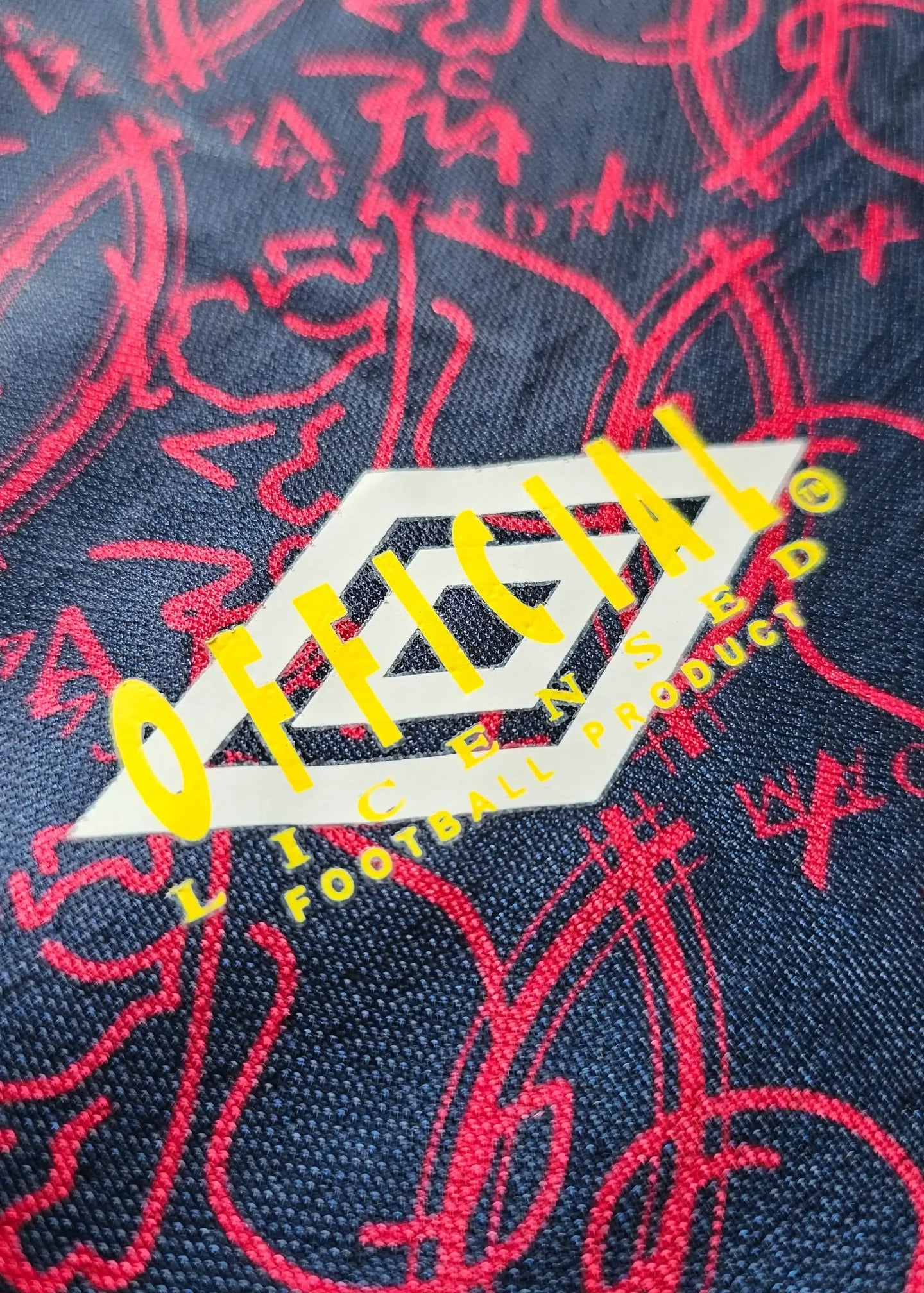 Detail view showing the 'OFFICIAL LICENSED FOOTBALL PRODUCT' tag on a signed soccer jersey.