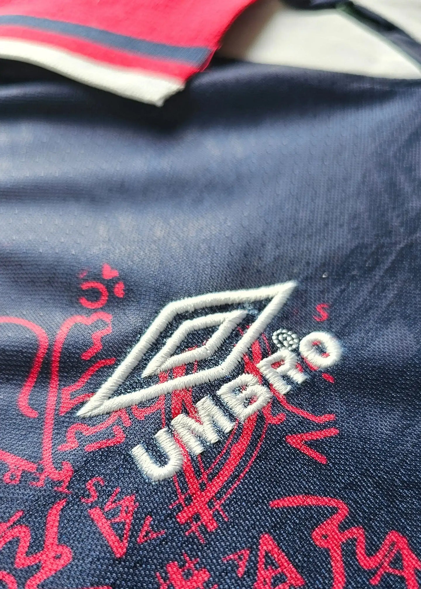 Close-up of the crest detail showing embroidered Umbro logo and Ajax design.