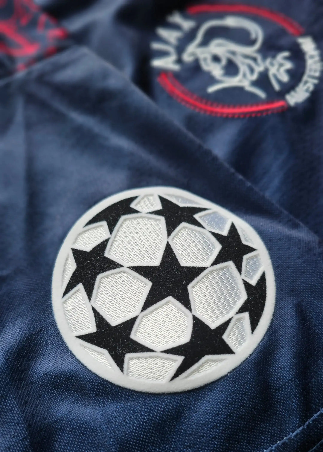 Close-up of Ajax crest with the iconic UEFA Champions League star ball detail.