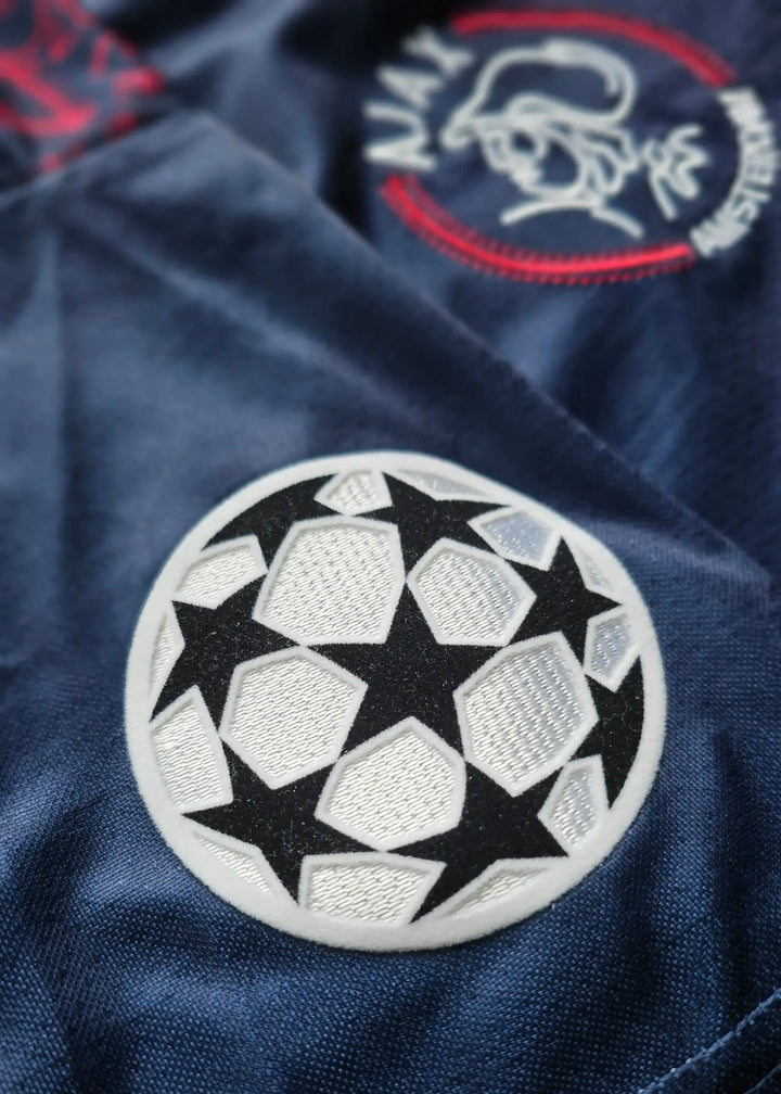 Close-up of Ajax crest with the iconic UEFA Champions League star ball detail.