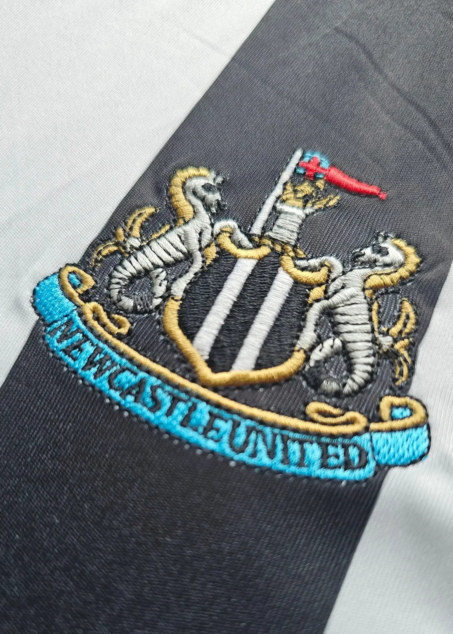 Close-up of the Newcastle United crest featuring two sea lions and the text 'NEWCASTLE UNITED'.