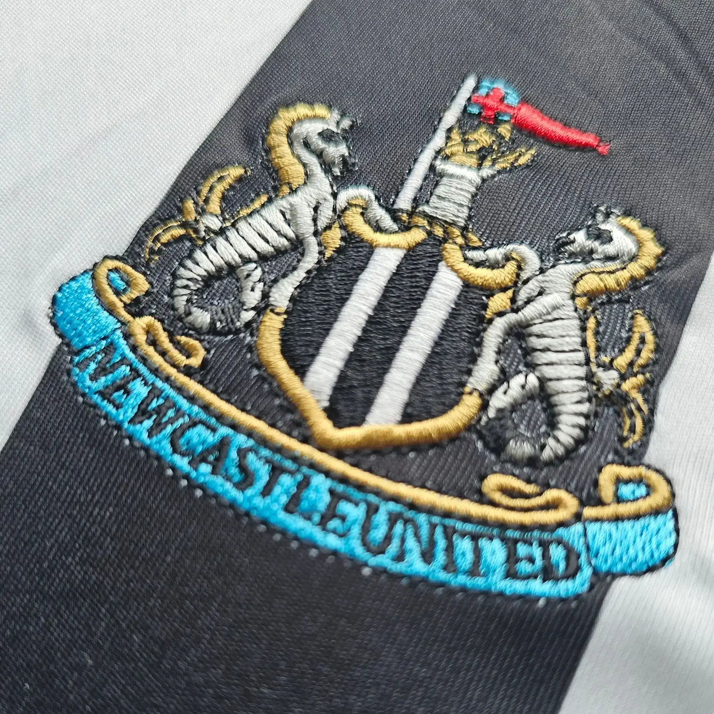 Embroidered Newcastle United logo on a sports jersey