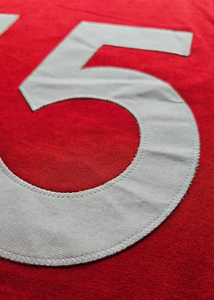 Close-up of the number 15 in white stitching on a red Ajax jersey.