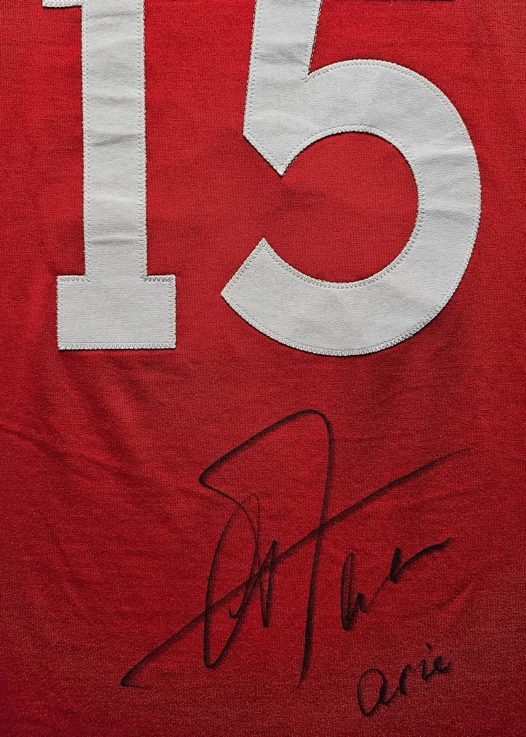 No. 15 in white on a red shirt, featuring the signature of Arie Haan.
