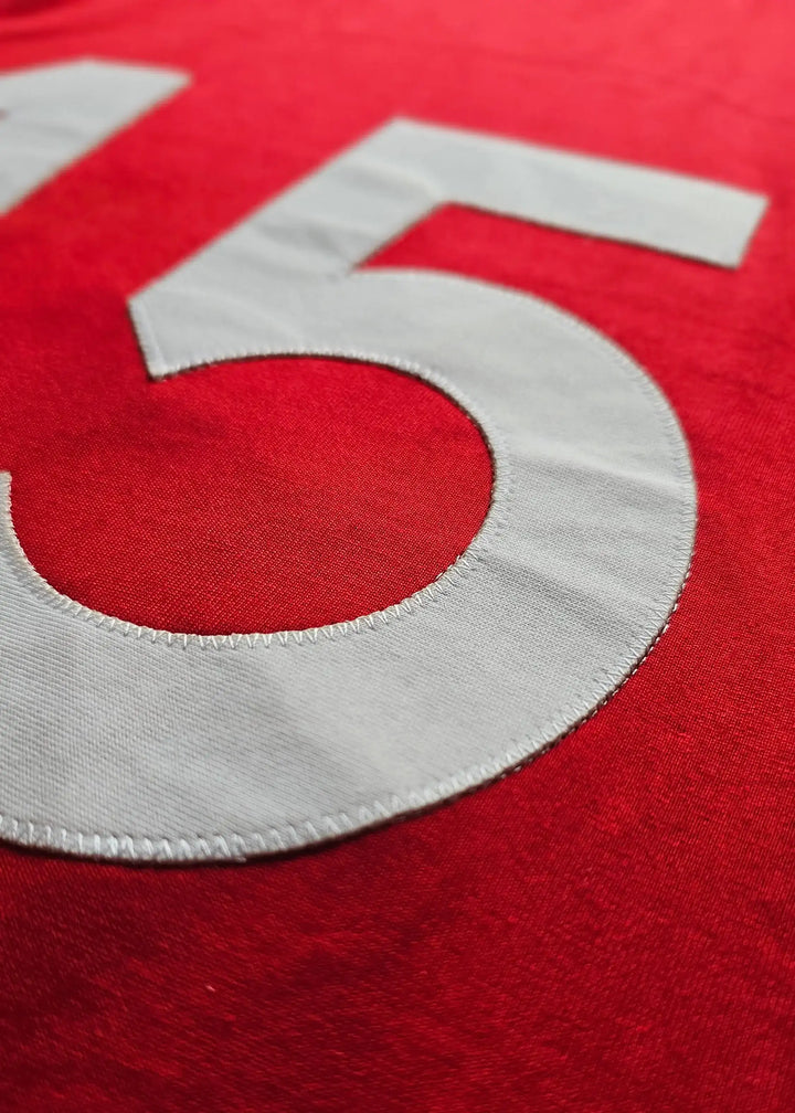 Close-up of the number 25 in white stitching on a red football shirt.