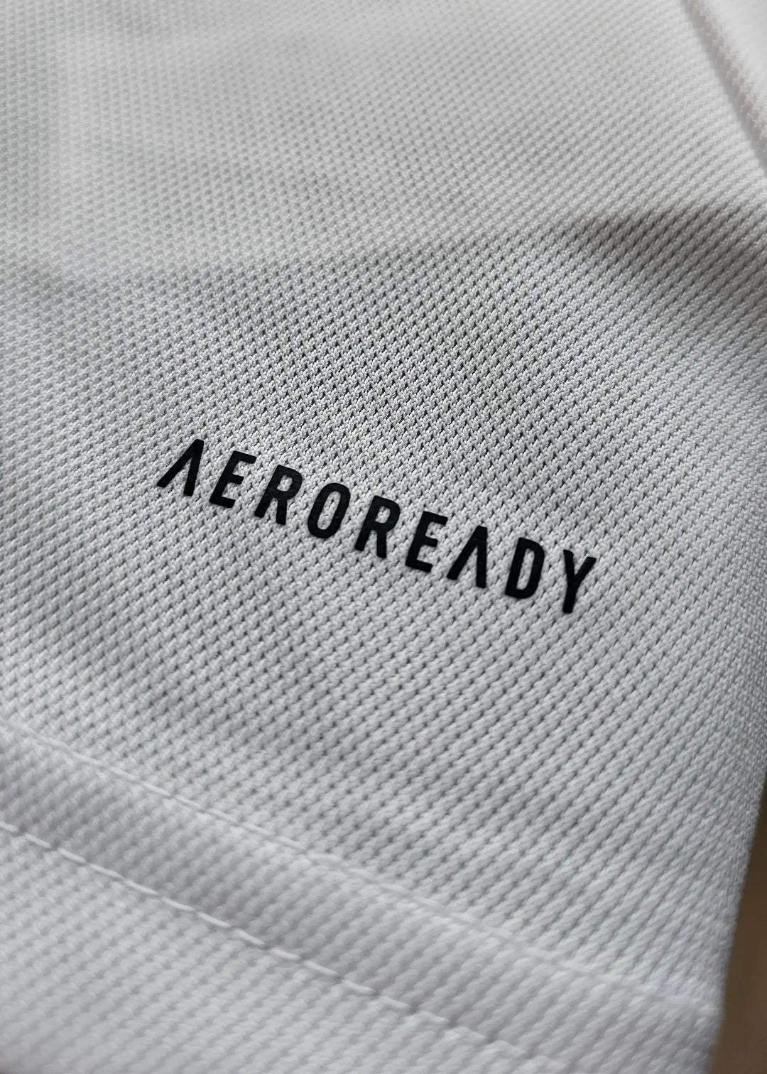 Close-up of the fabric showing the AEROREADY logo in black on a white background.