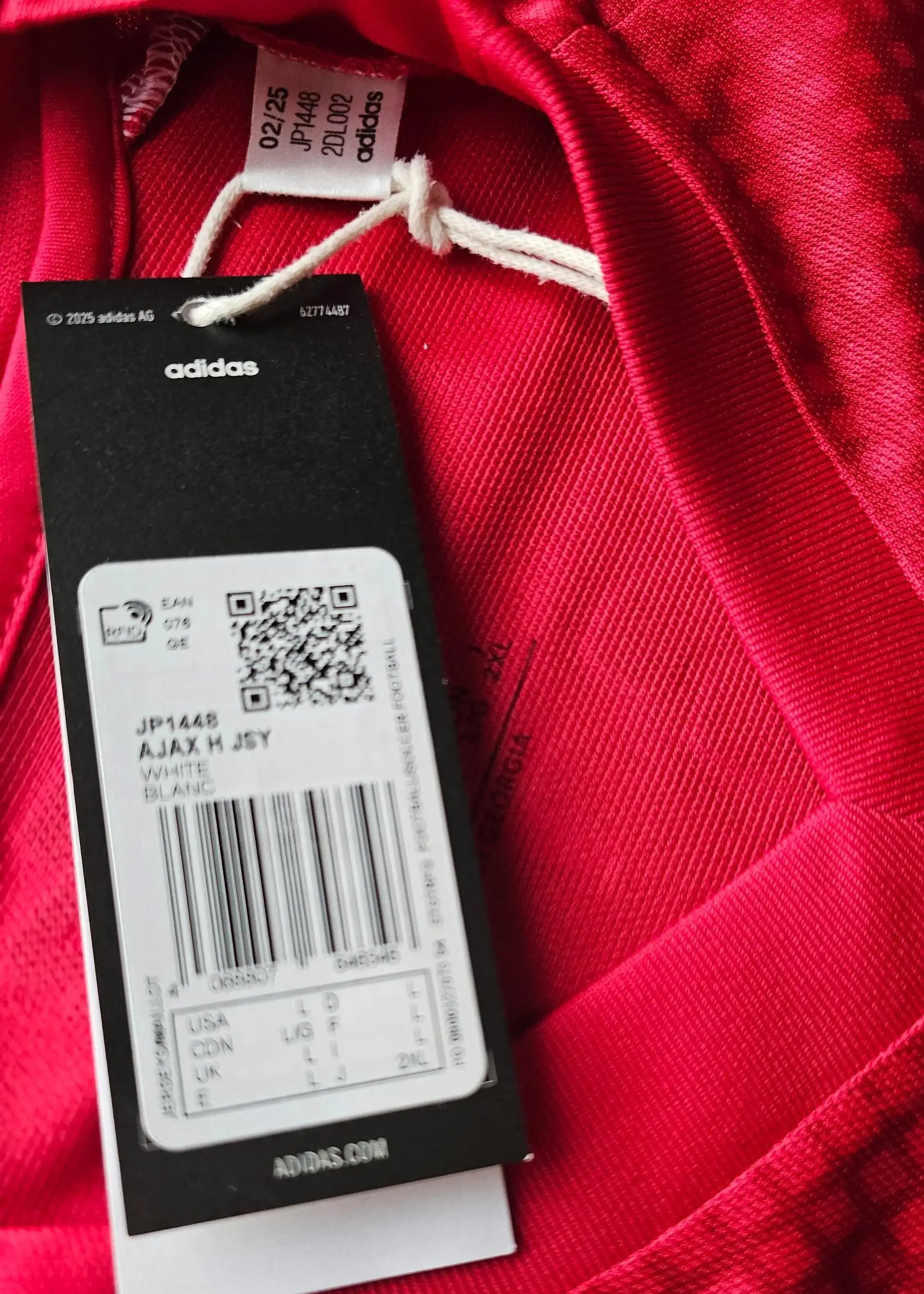 Tag detail of a red Ajax football shirt, featuring adidas branding and care label information.