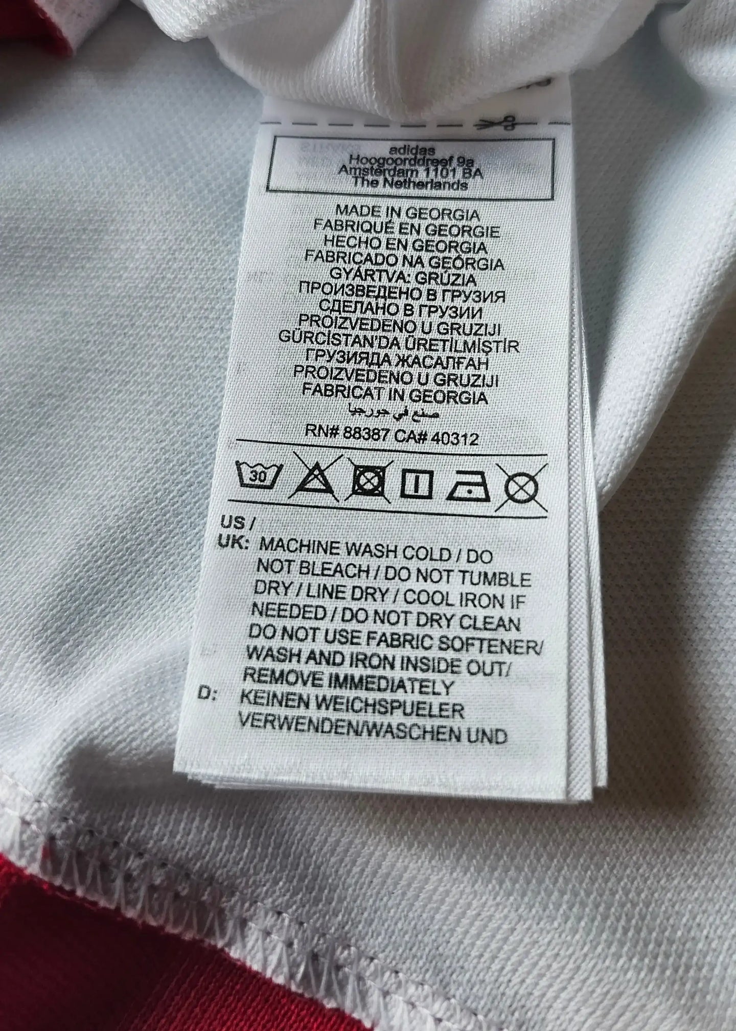 adidas care label with washing instructions, made in Georgia, multiple languages visible.