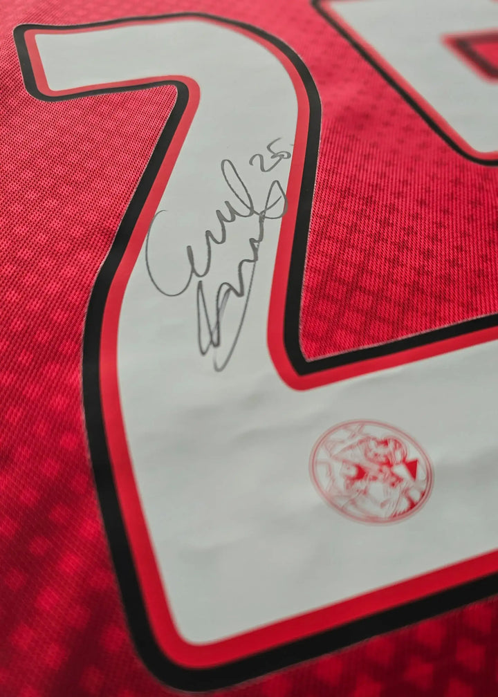 Close-up of the No. 25 featuring a signature on a red Ajax football shirt.