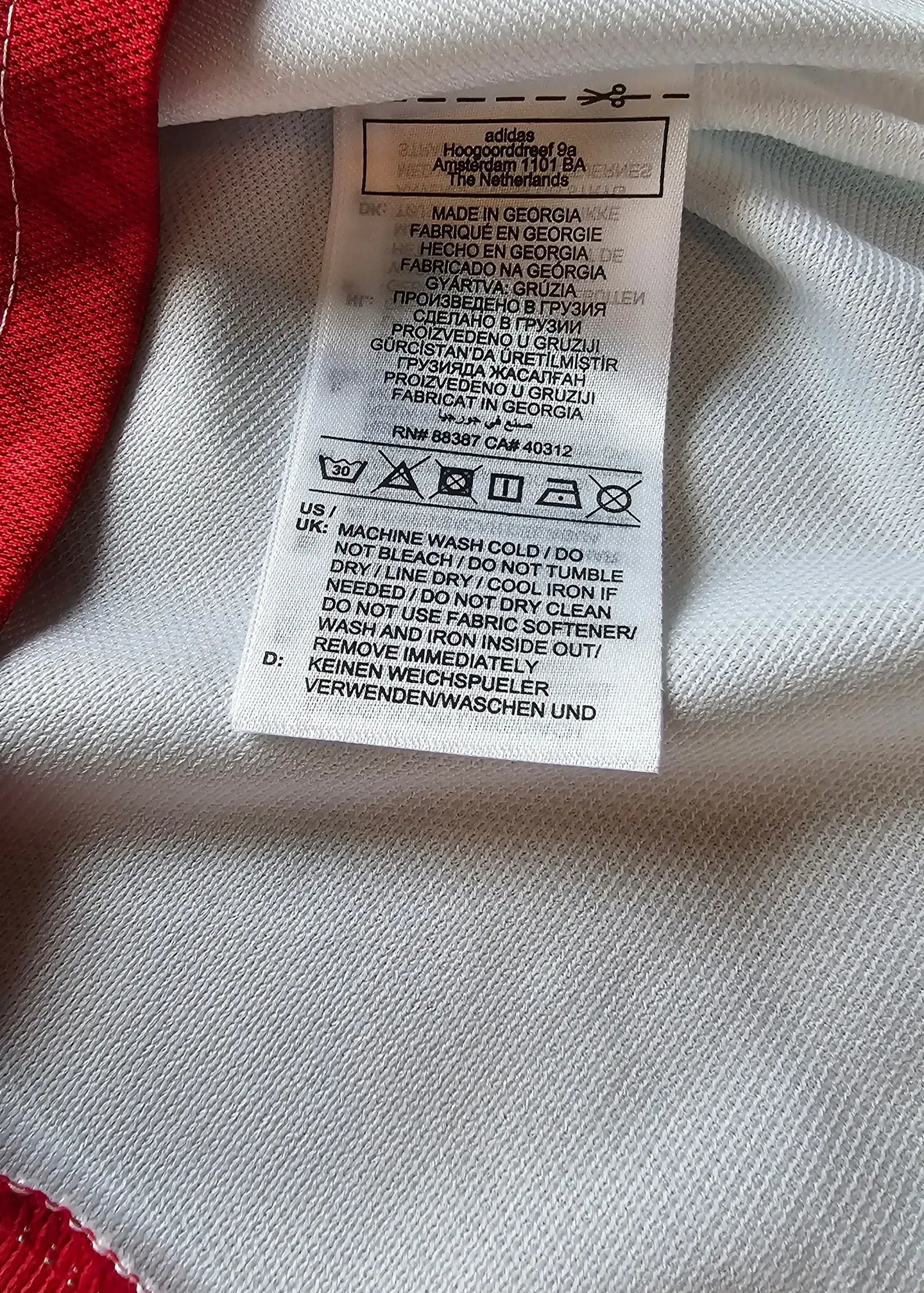Care label showing washing instructions and adidas branding on the inside of the jersey.