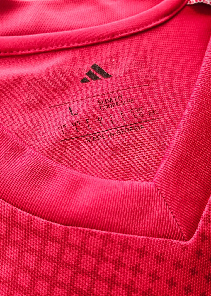 Inside collar view displaying size label L and adidas logo on a red football shirt.