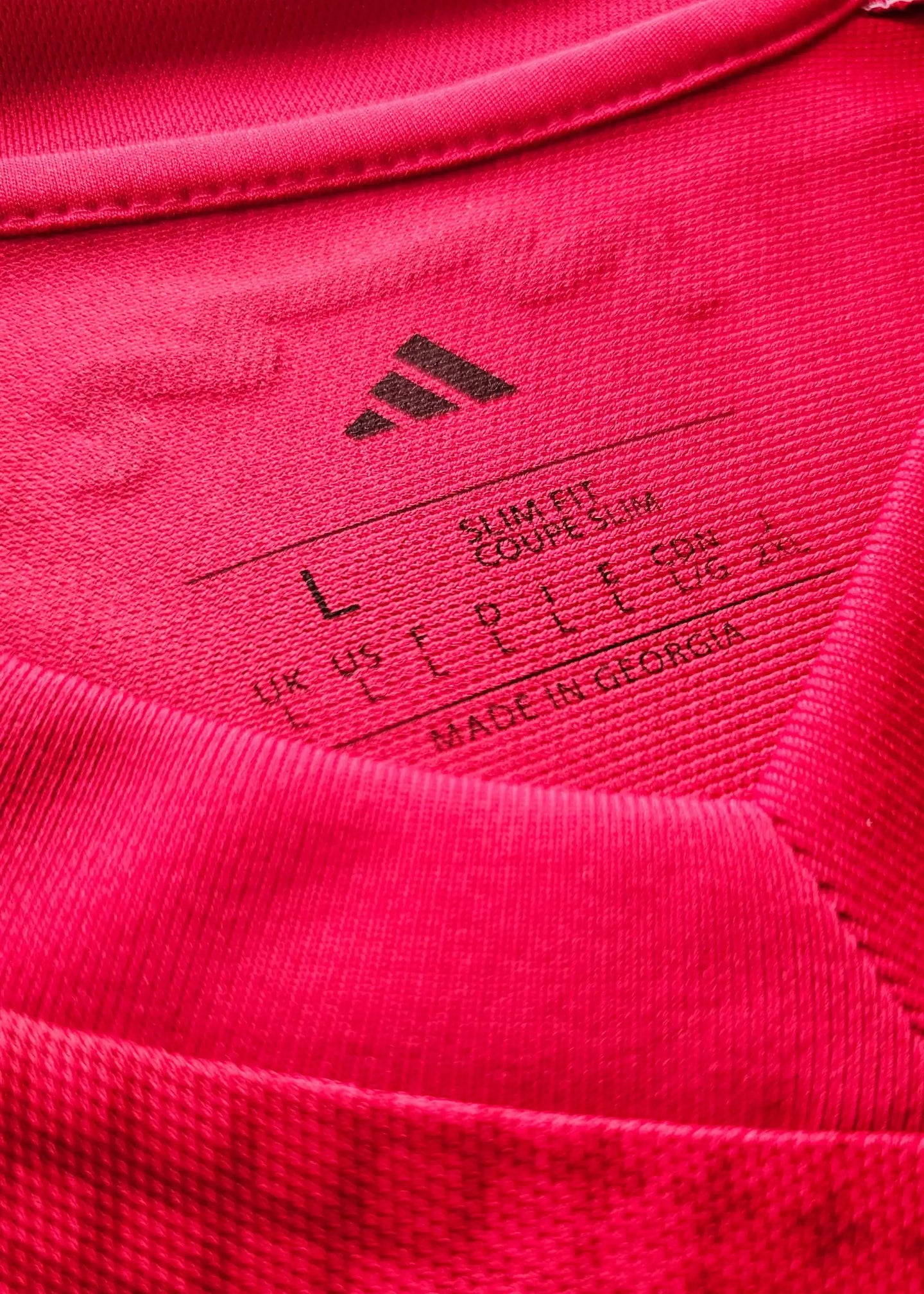 Close-up of garment label showing size L and adidas logo on a pink soccer jersey.