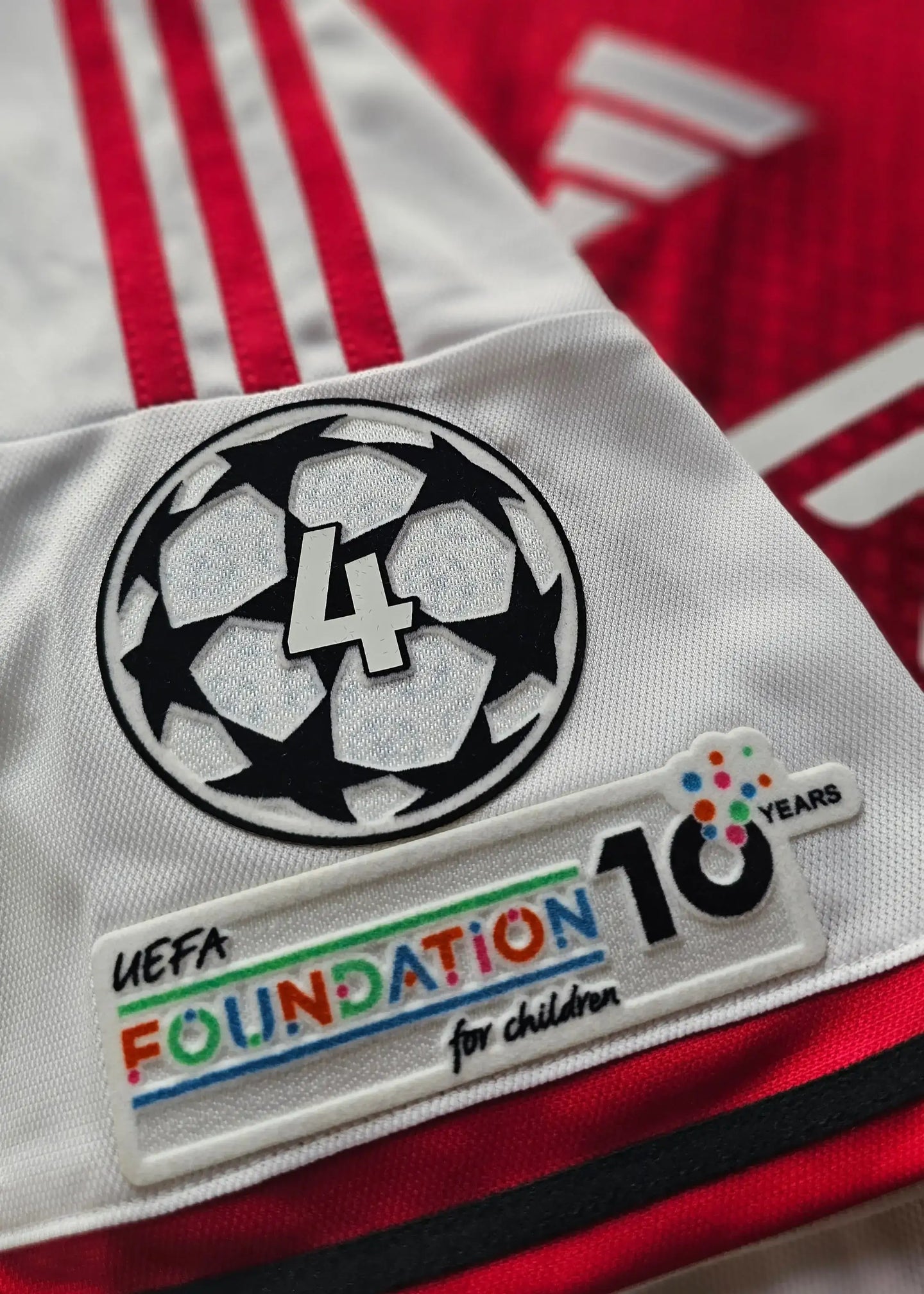 Champions League patch featuring a black and white star ball with '4' and 'UEFA FOUNDATION 10 YEARS' label.