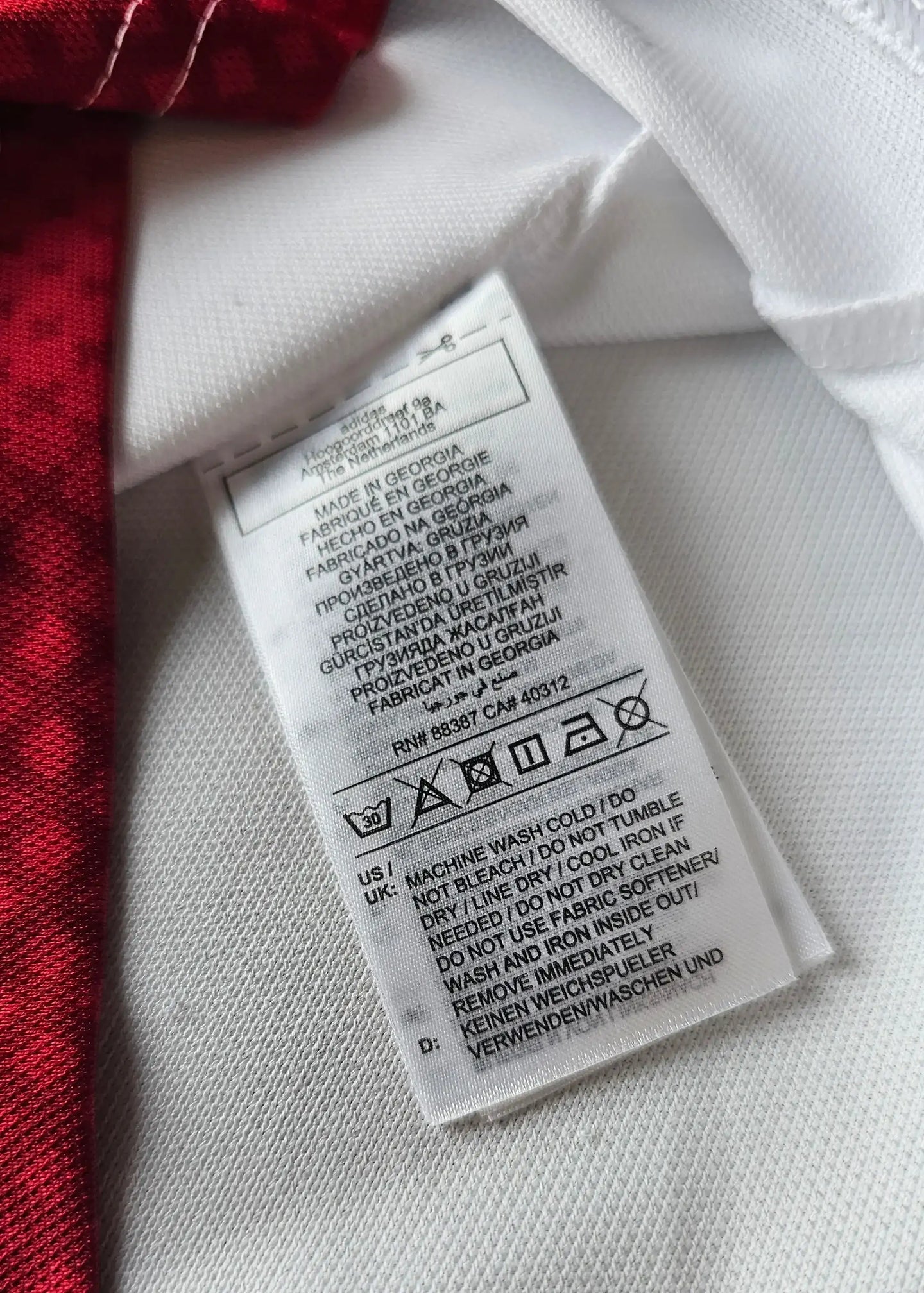 Label detailing care instructions on the Wout Weghorst Ajax signed jersey, showing washing guidelines.