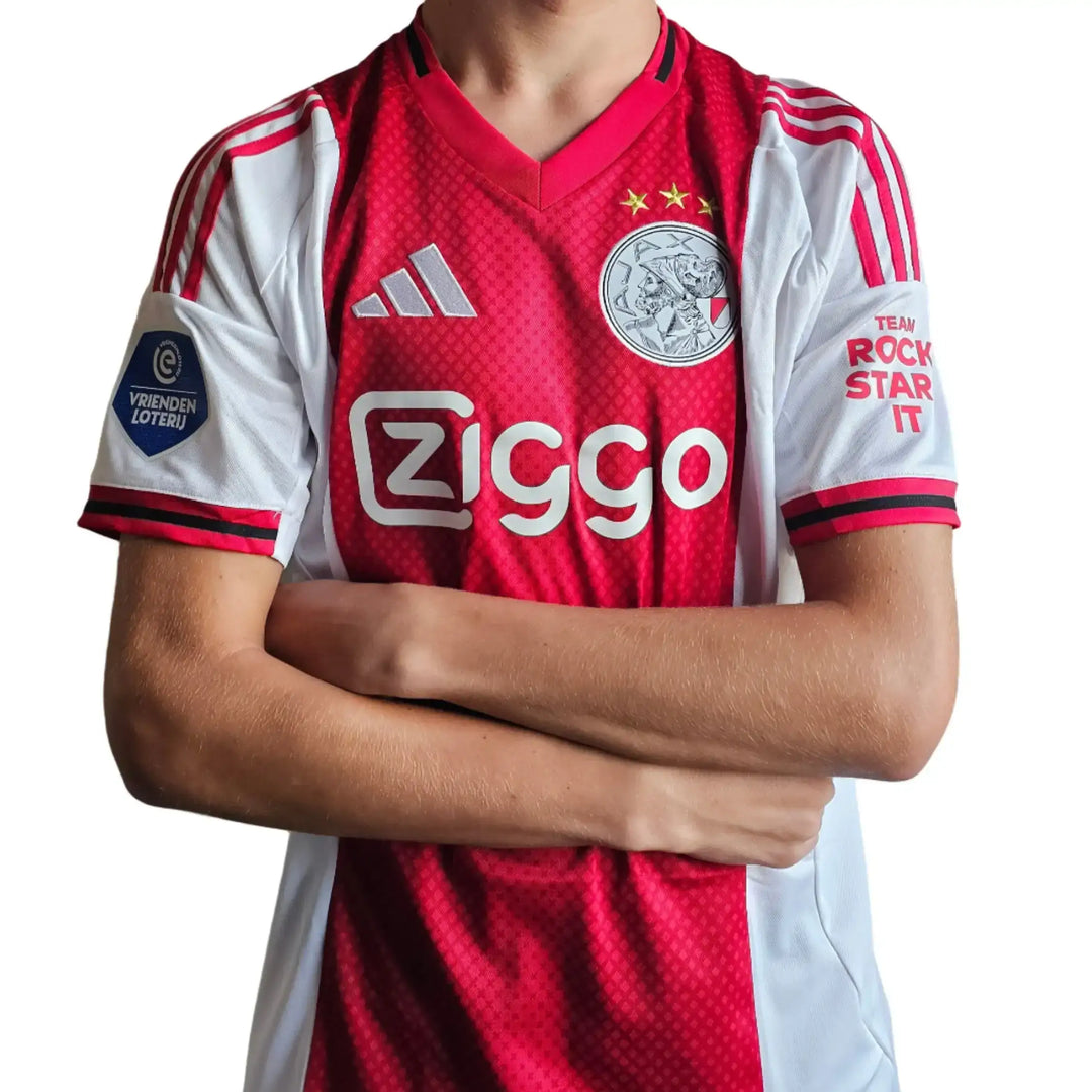 Ajax home shirt with red and white colors, features two stars, Ziggo sponsor, and VRIENDEN LOTERIJ logo.