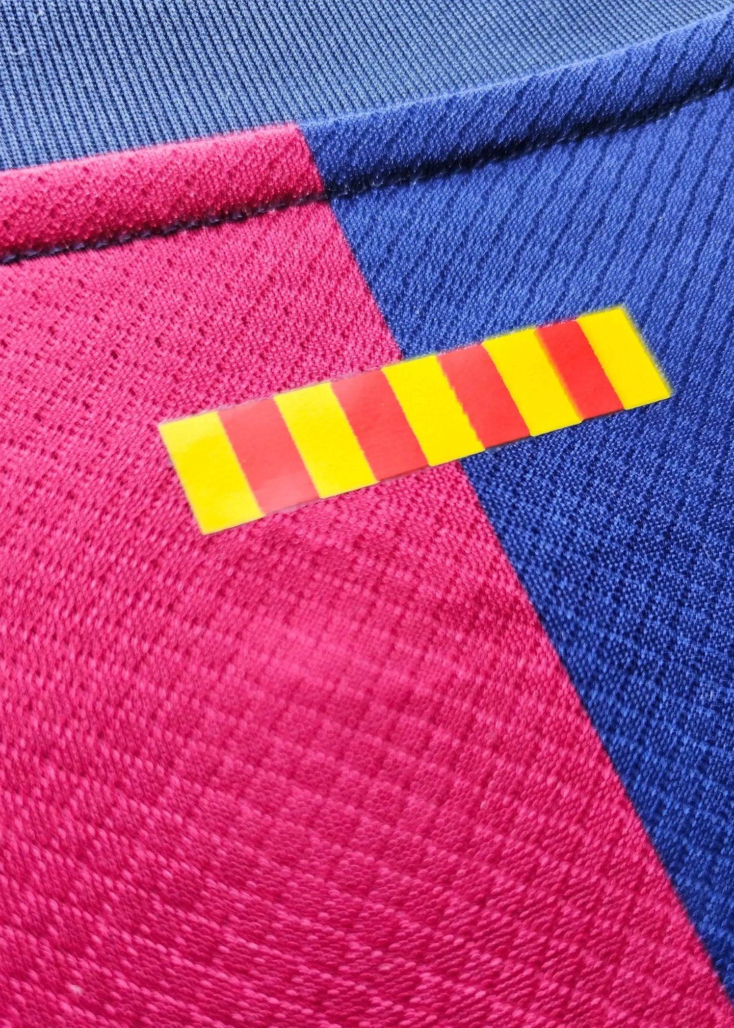 Detail of the FC Barcelona 2024-2025 shirt featuring a red and yellow striped label.