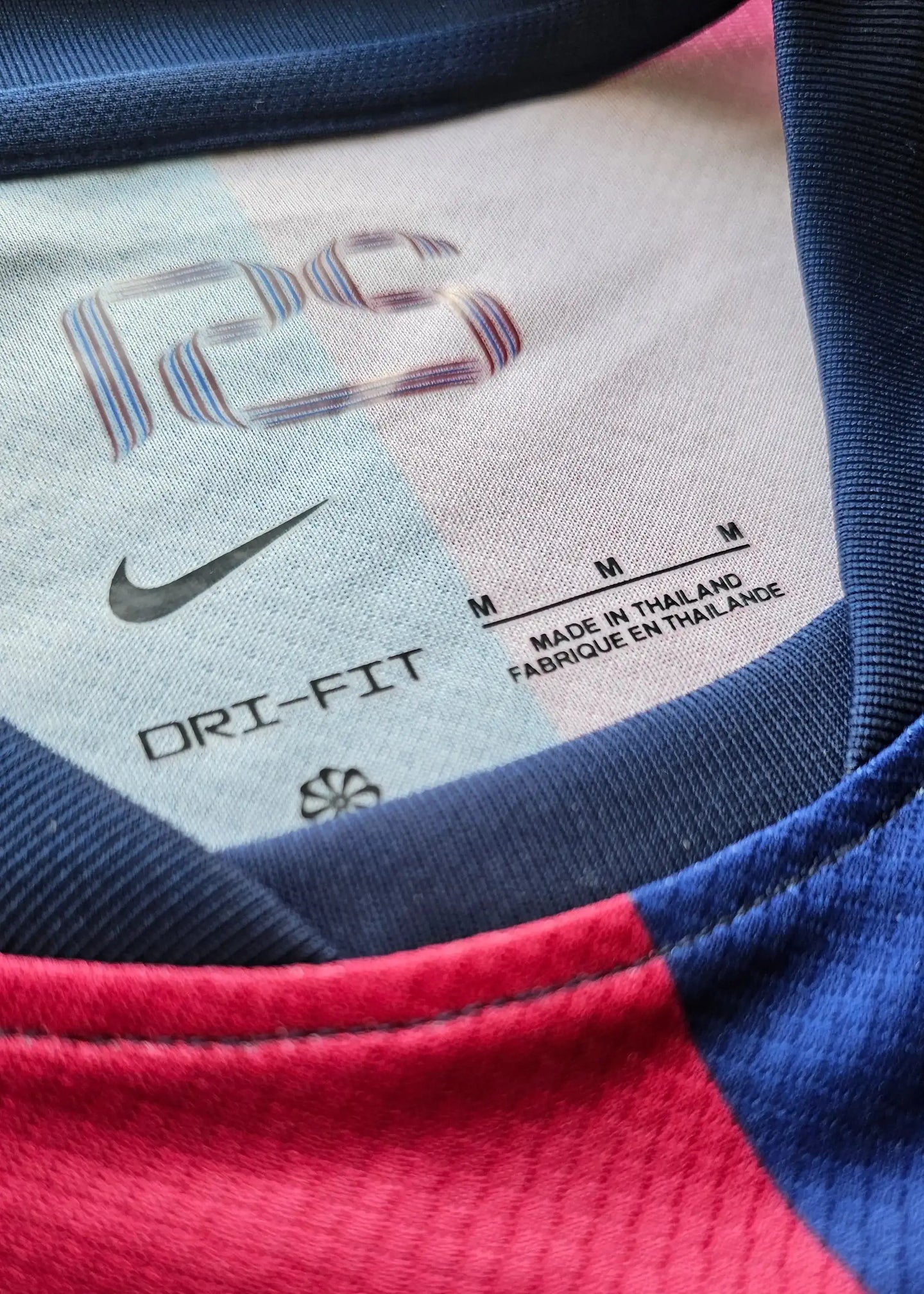 Nike DRI-FIT label on the collar of a blue and red football shirt, size M, made in Thailand.