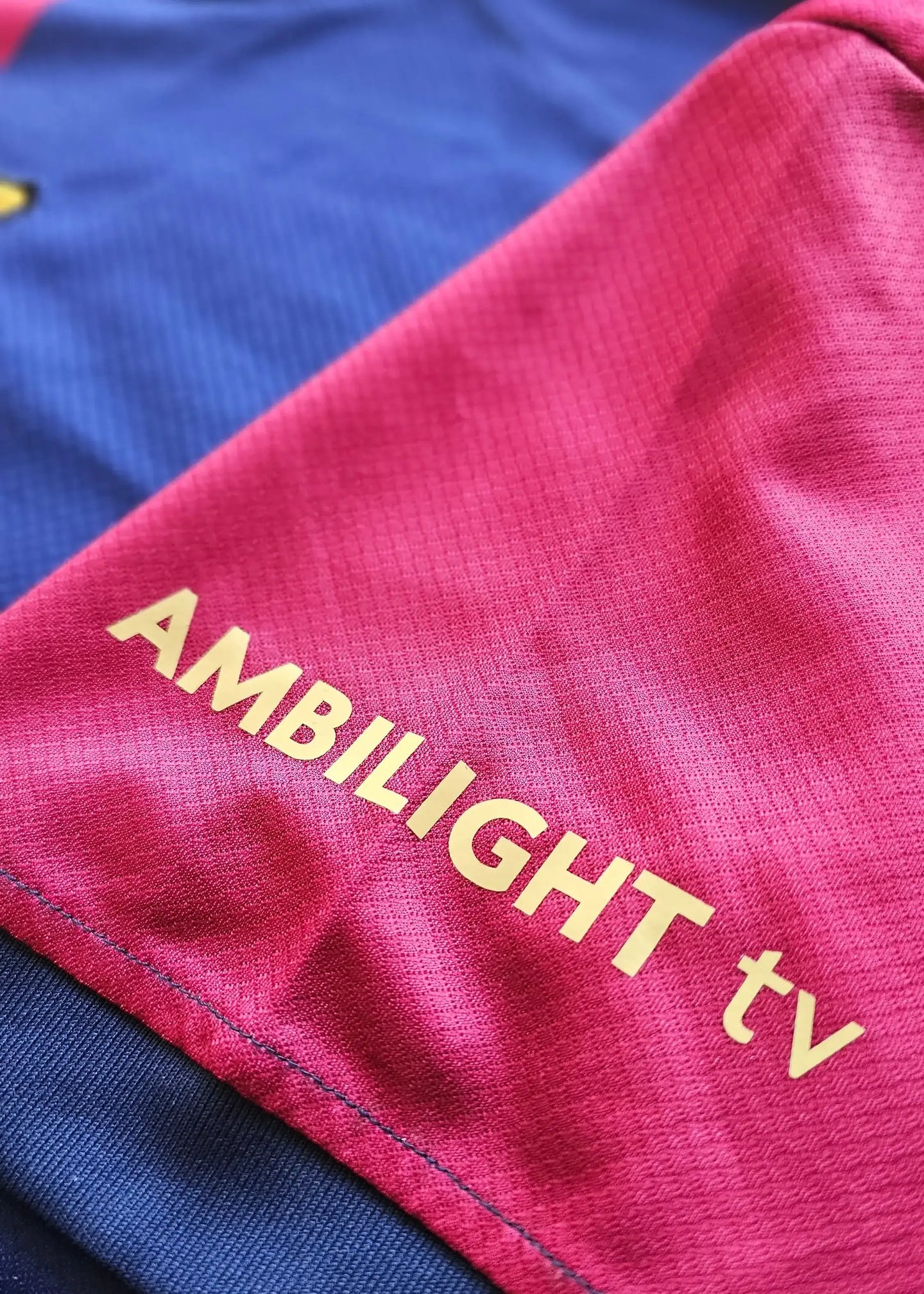 Close-up of the left sleeve of the Barcelona 2024-2025 shirt featuring the text AMBILIGHT tv in gold.