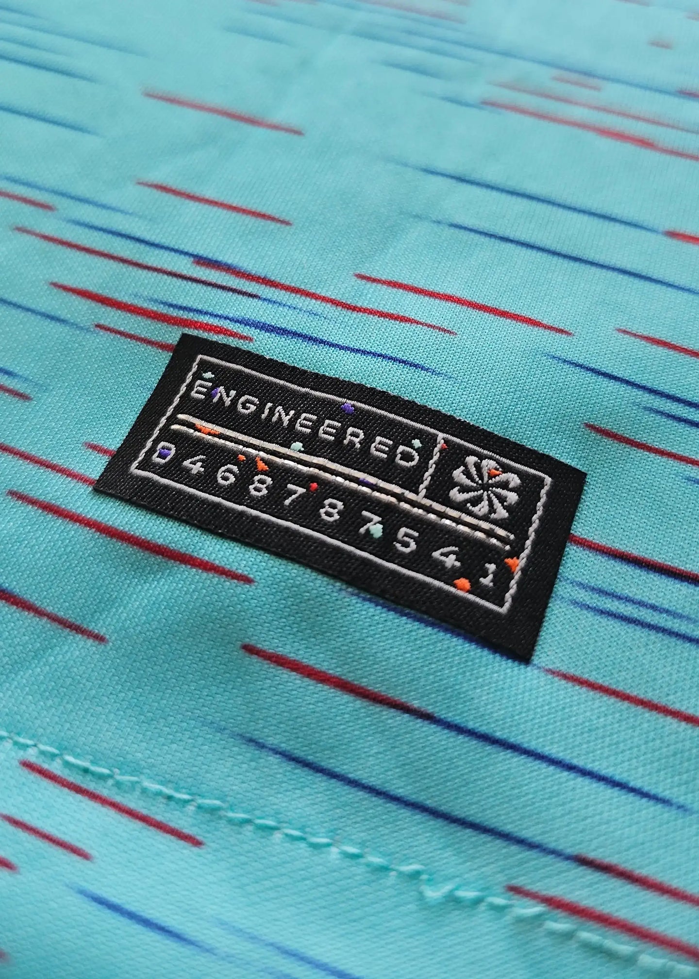 Detail of the engineered label on a blue and green football shirt with colorful accents.