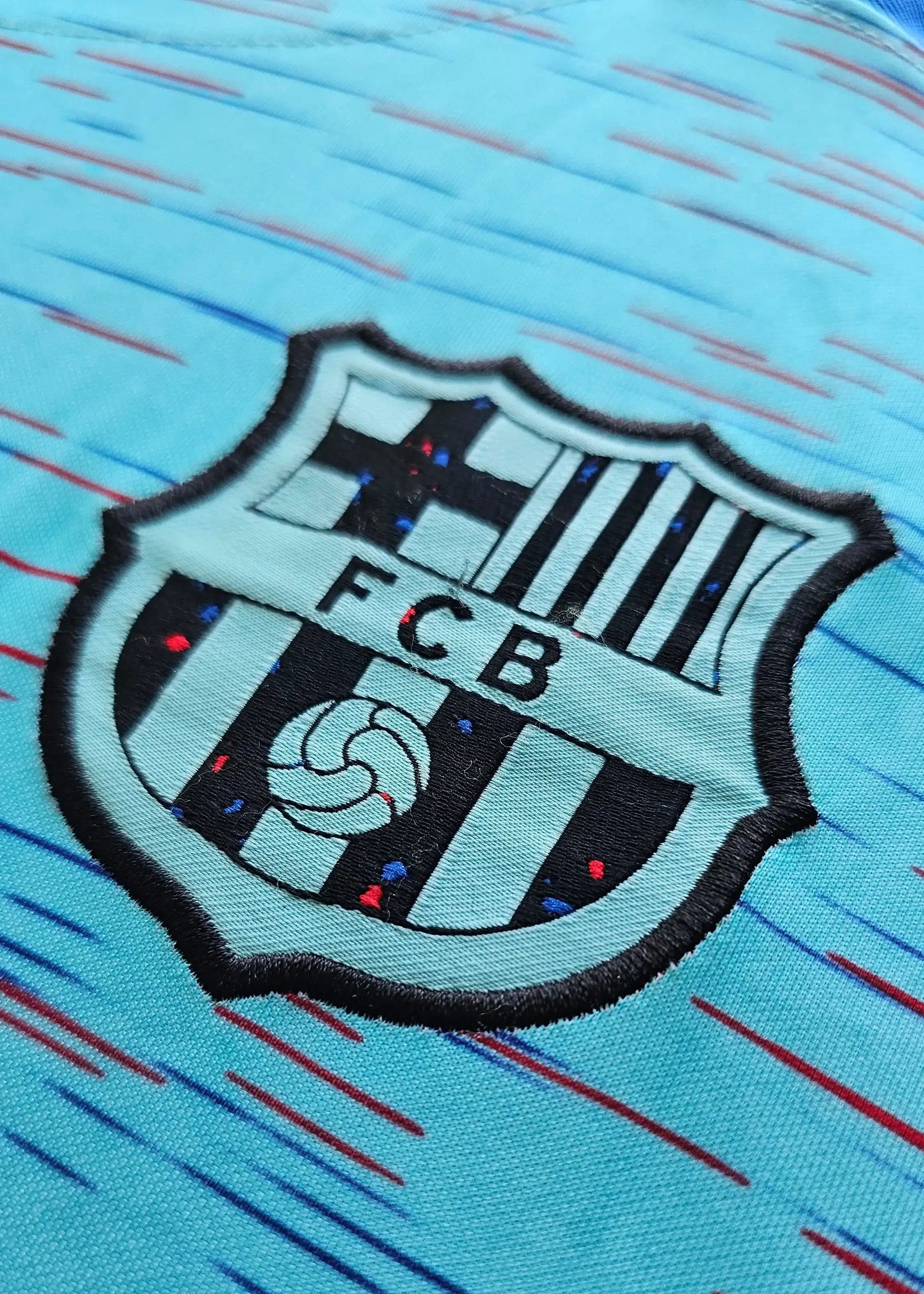 FC Barcelona crest with blue and green gradient background on signed football shirt.