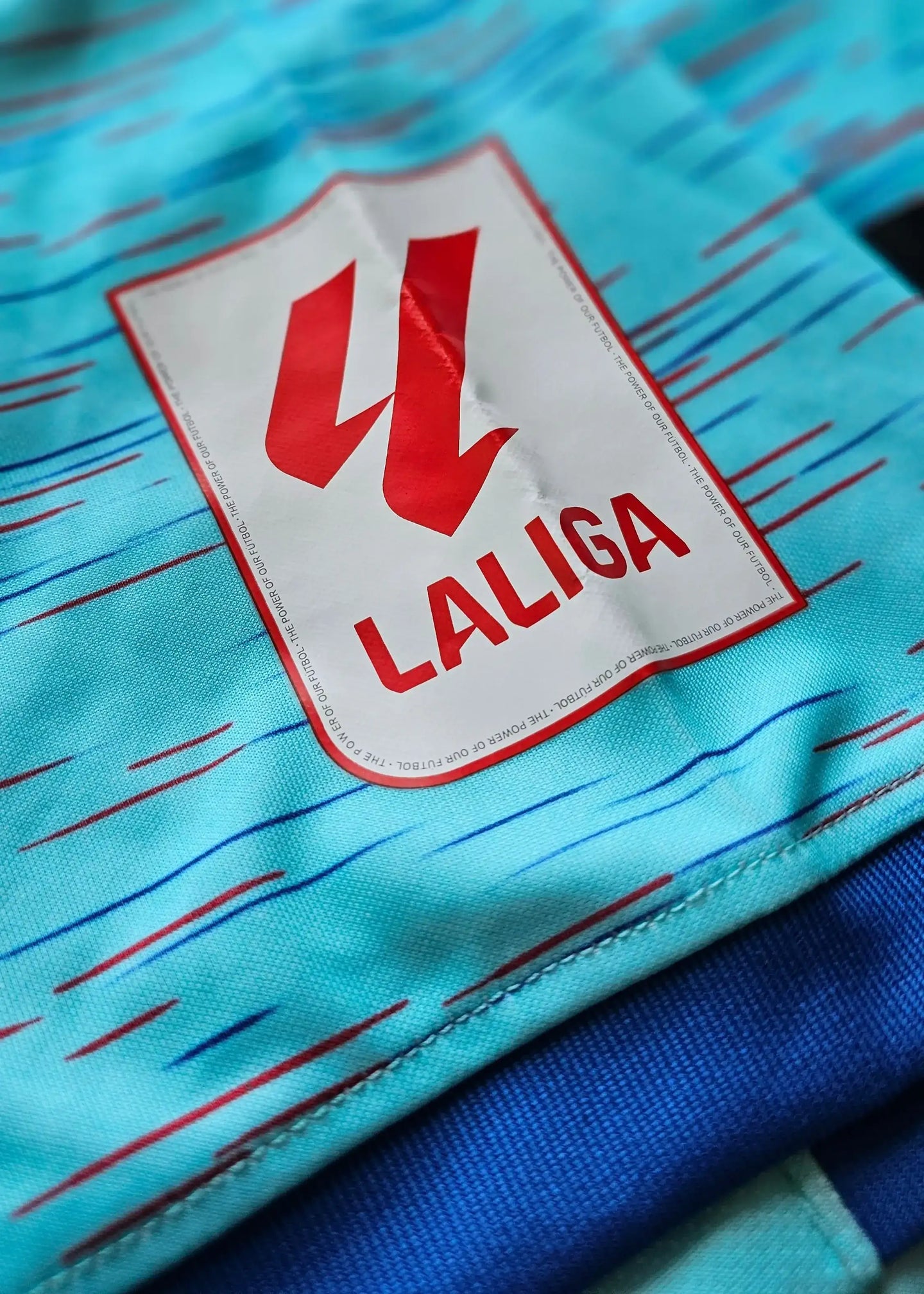 LALIGA logo in red on a blue shirt with abstract design details.