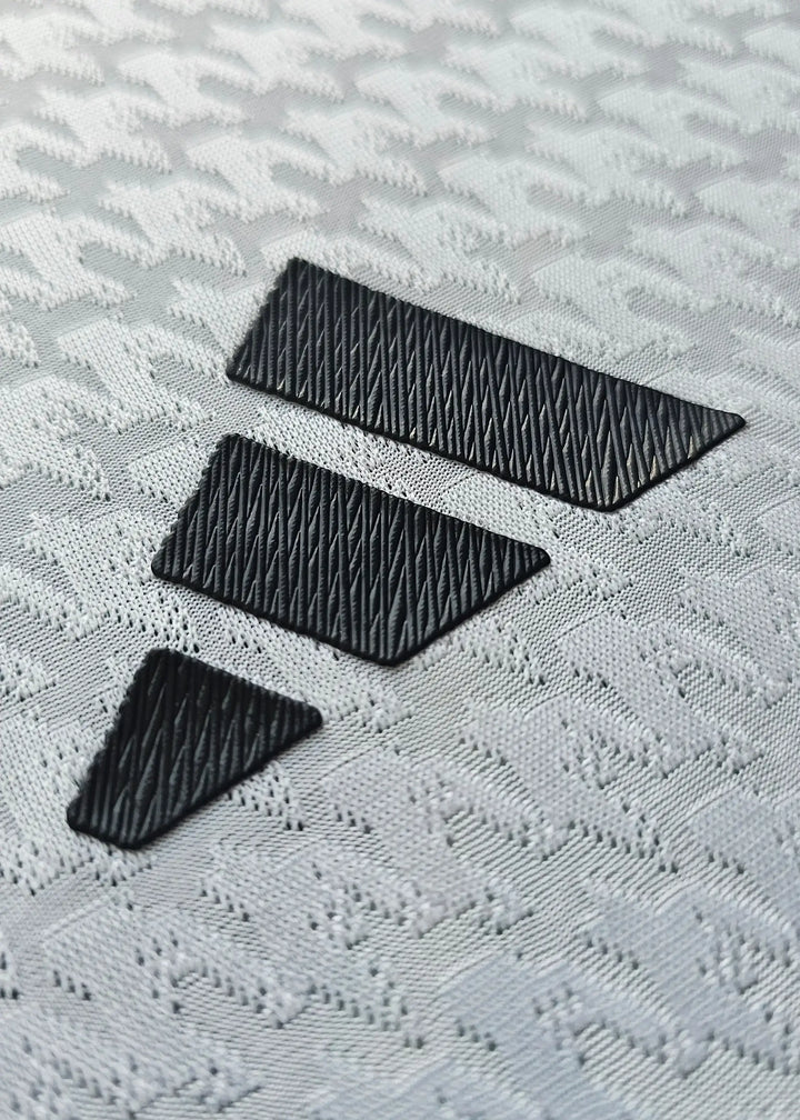 Close-up view of three black adidas stripes on a textured white football shirt fabric.