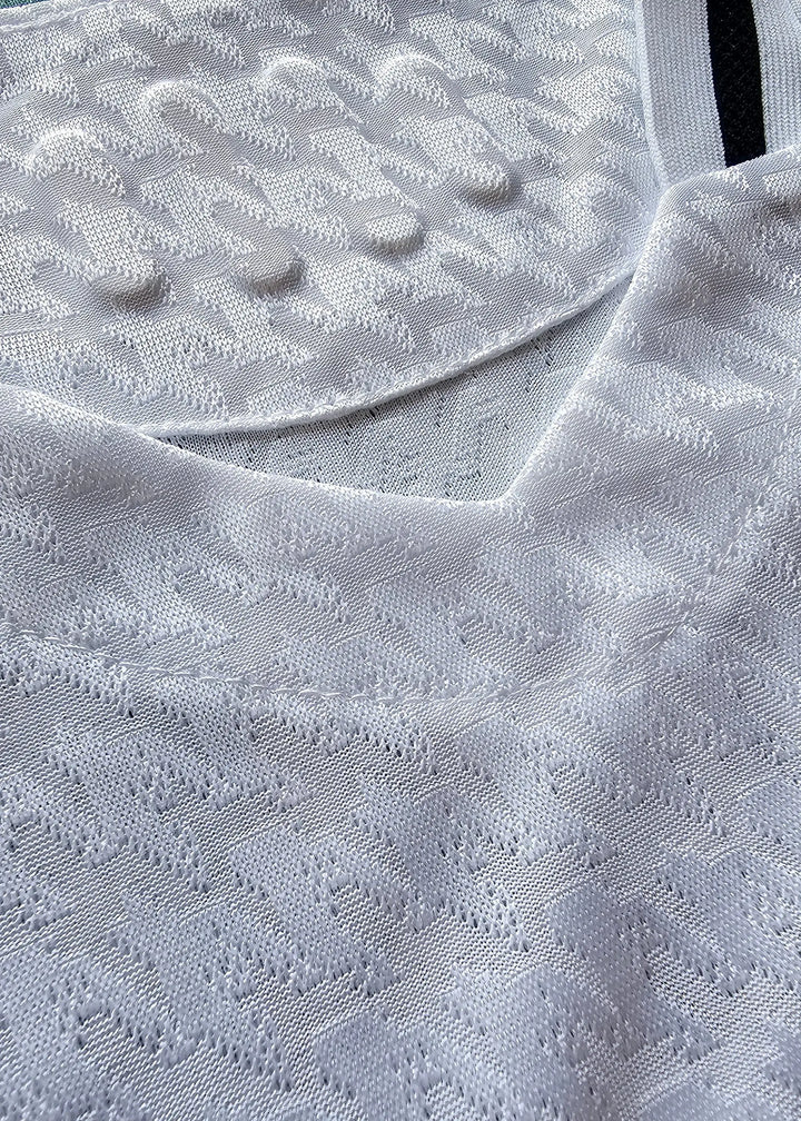 Close-up of the collar and textured fabric on a white football shirt with detailed stitching.