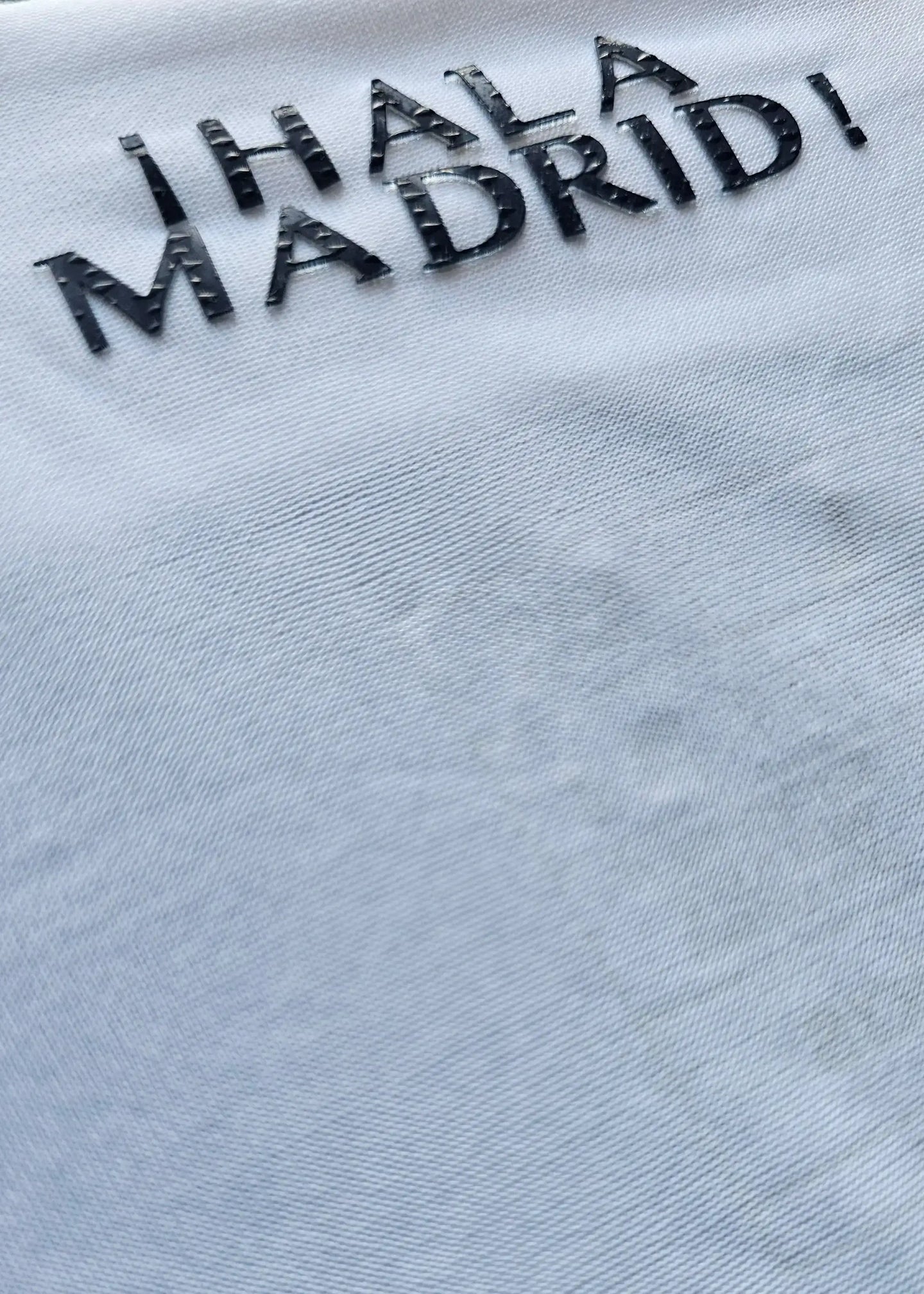Detail highlighting the embroidered text '¡Hala Madrid!' on a white football shirt.