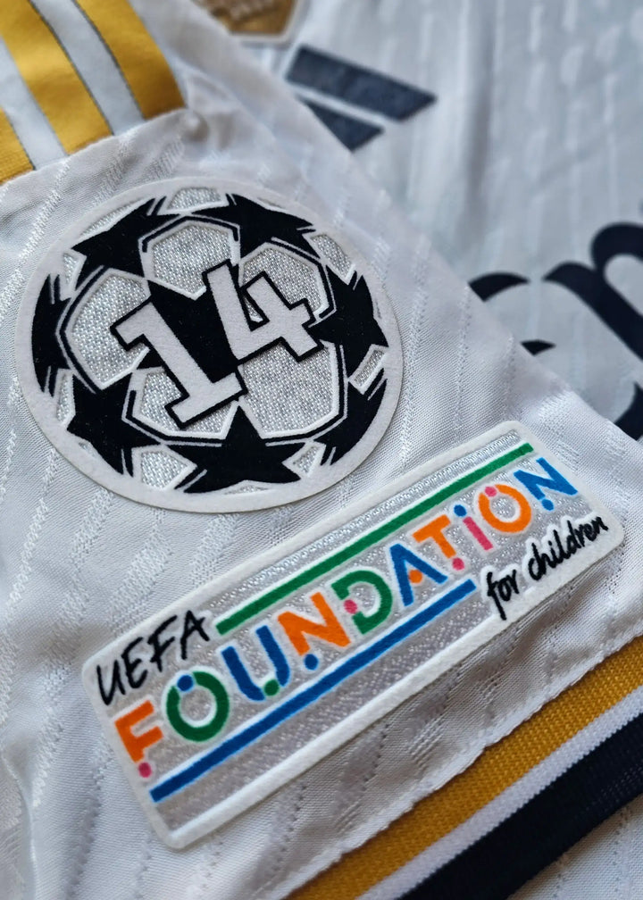 Close-up of a white football shirt featuring UEFA FOUNDATION for children patch and No. 5 badge.