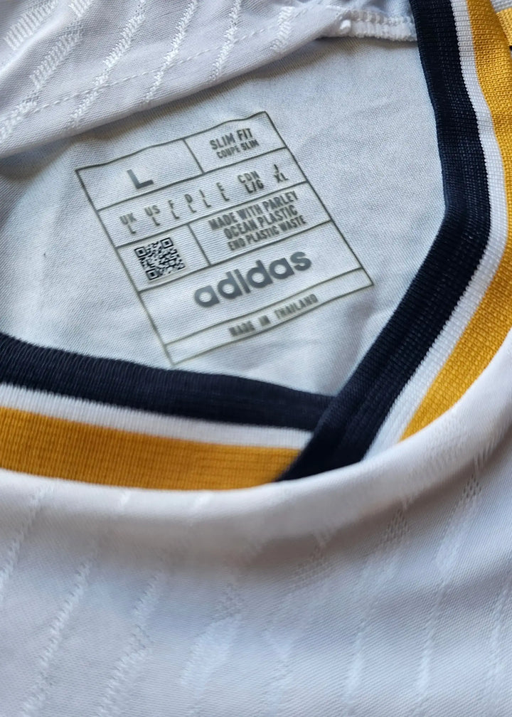 Size L label showing "adidas" brand, slim fit details, care instructions and QR code.
