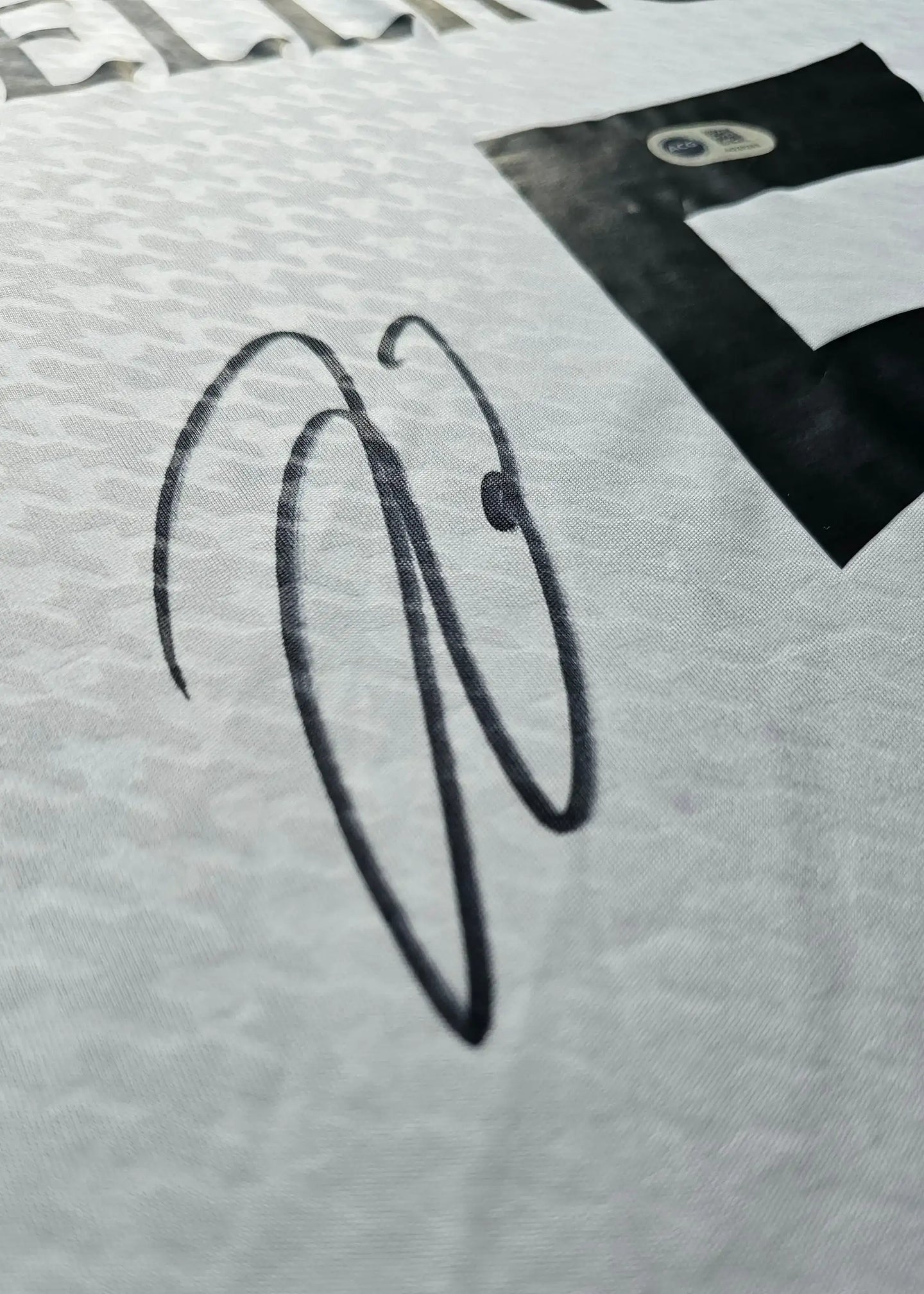 Signature detail of Jude Bellingham on the Real Madrid signed football shirt.