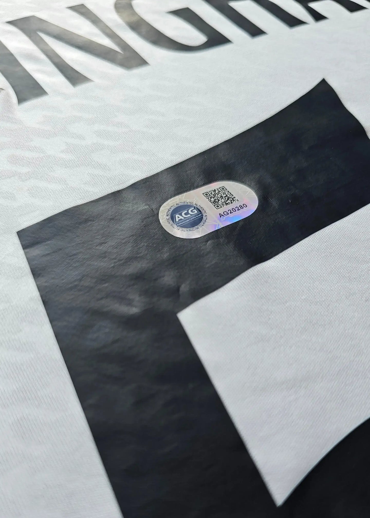 View of the signature detail and authenticity label on Jude Bellingham 5 Real Madrid shirt.