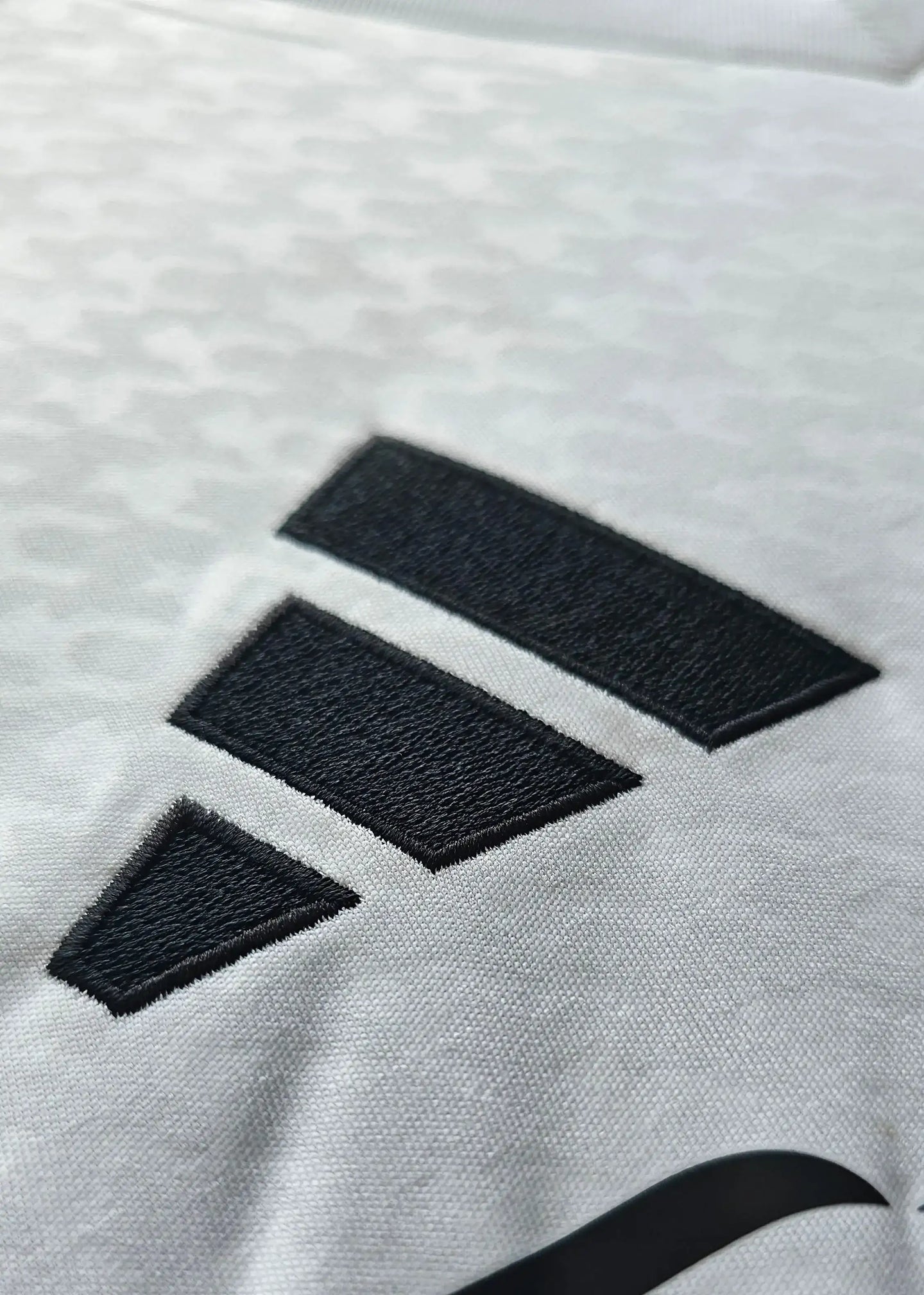 Close-up of the black adidas emblem on the Jude Bellingham signed Real Madrid shirt.