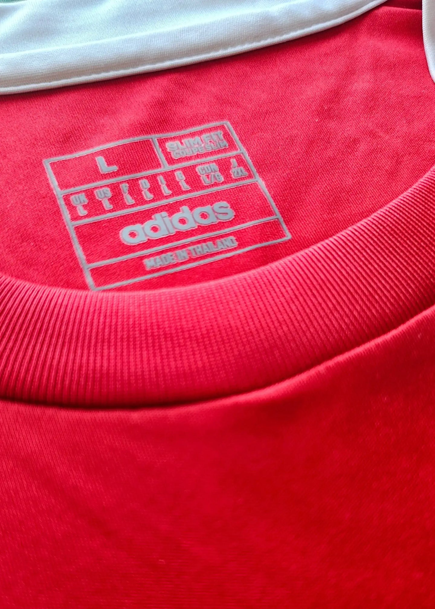 Size L care label featuring adidas branding and 'MADE IN THAILAND' on a red shirt.