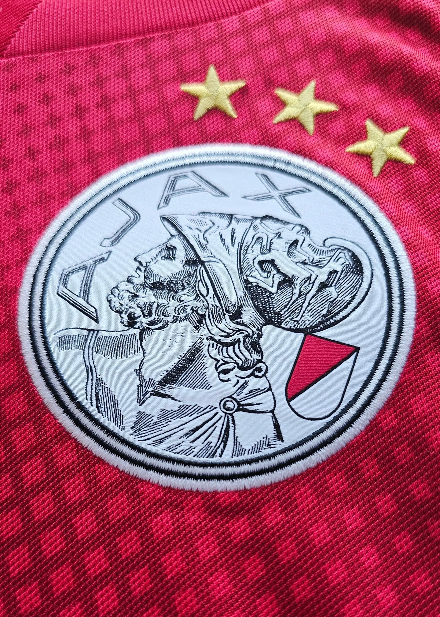 AJAX crest with three stars on a red background, featuring embroidered details.