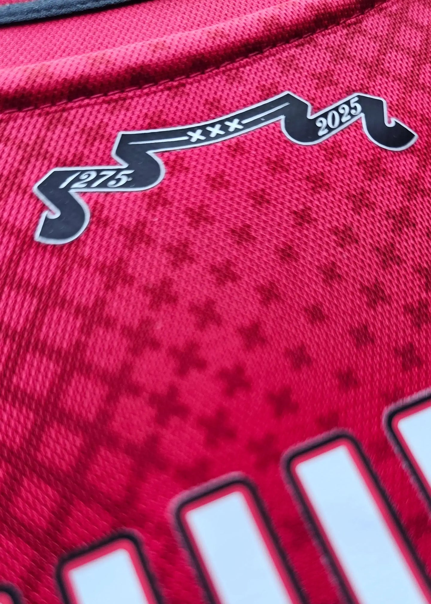 Close-up detail of the collar area with '1275' and '2025' on a red football shirt.