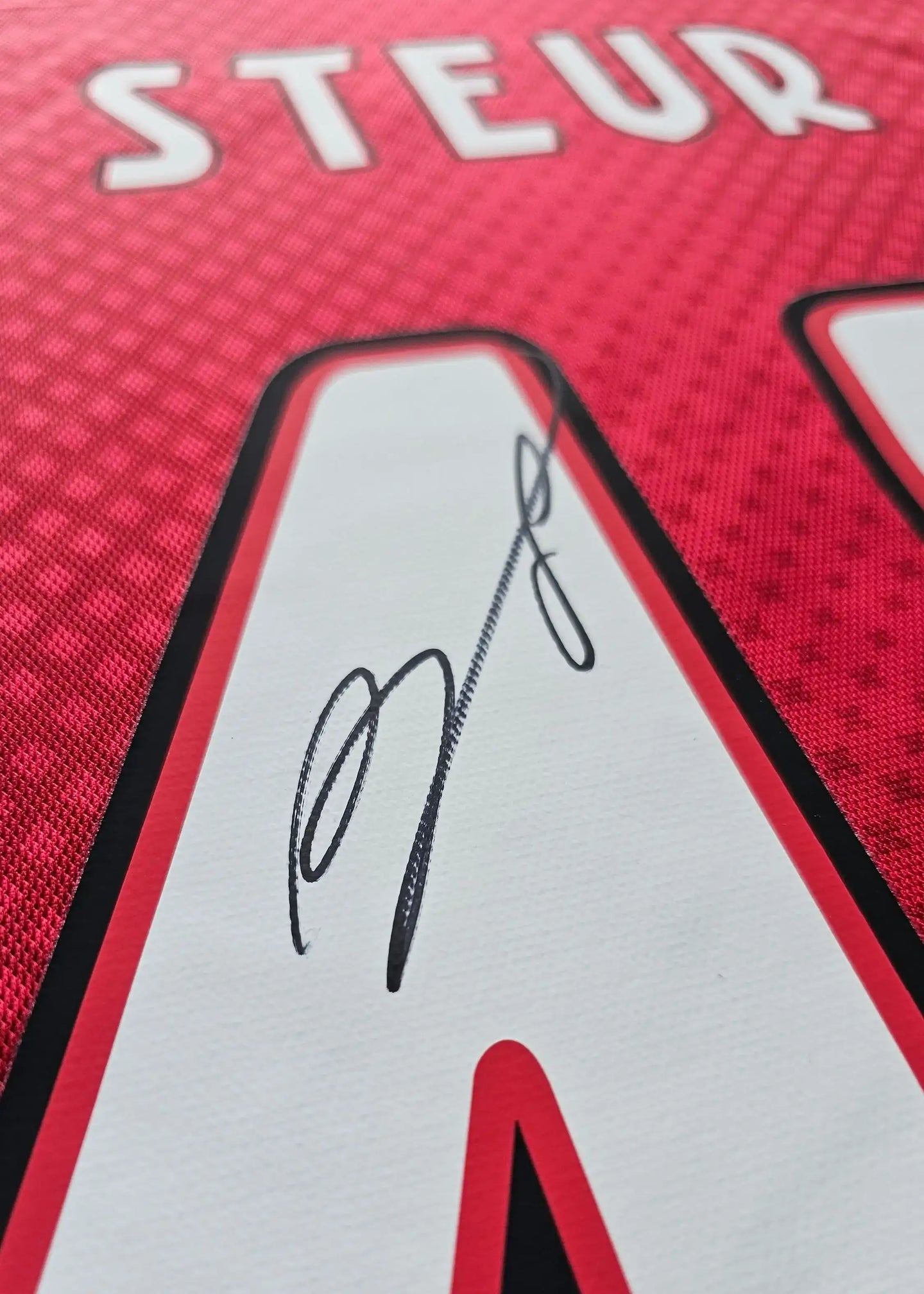 Close-up of the signature of Steur on red Ajax shirt featuring No. 48.