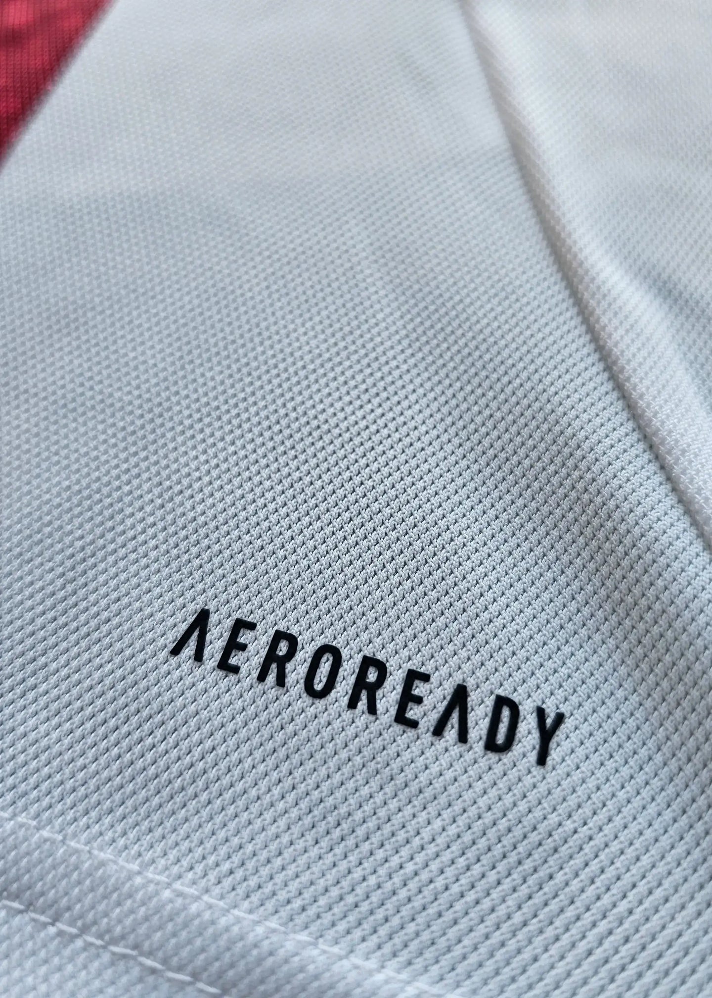 Close-up of the white 'AEROREADY' label on the Ajax shirt showing a red section.