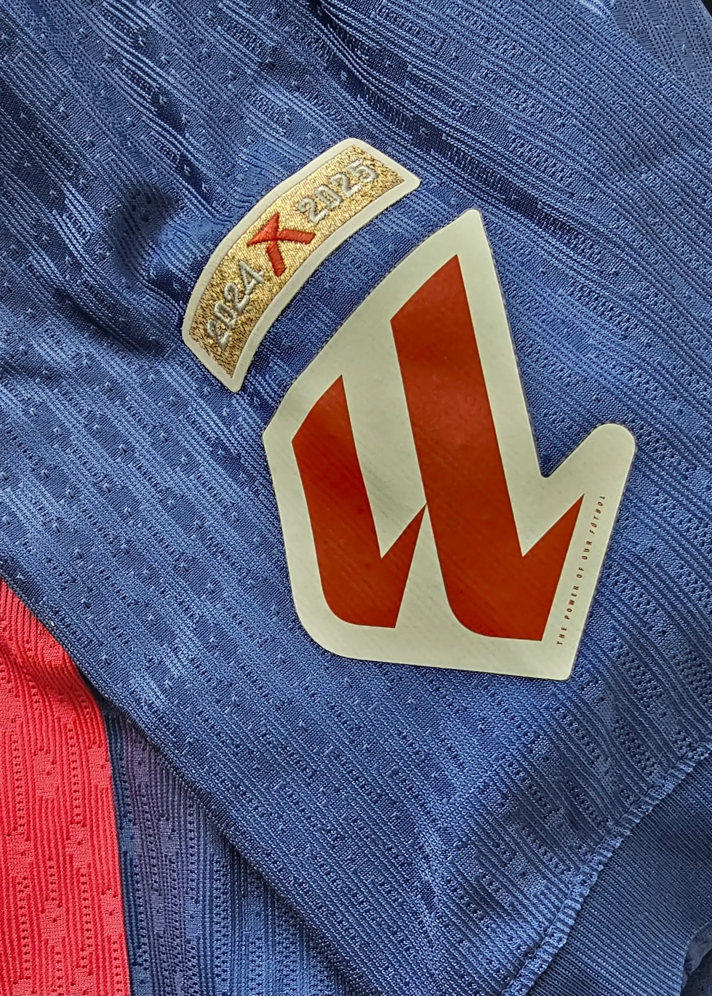 Detail view showing the 2024-2025 season tag and a red crest on the Barcelona shirt.