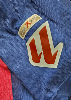 Detail view showing the 2024-2025 season tag and a red crest on the Barcelona shirt.