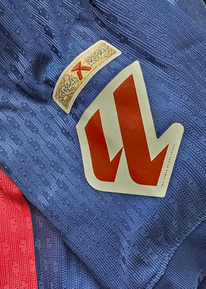 Detail view showing the 2024-2025 season tag and a red crest on the Barcelona shirt.