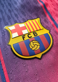 Close-up view of the FC Barcelona crest featuring red and blue stripes with FCB lettering.